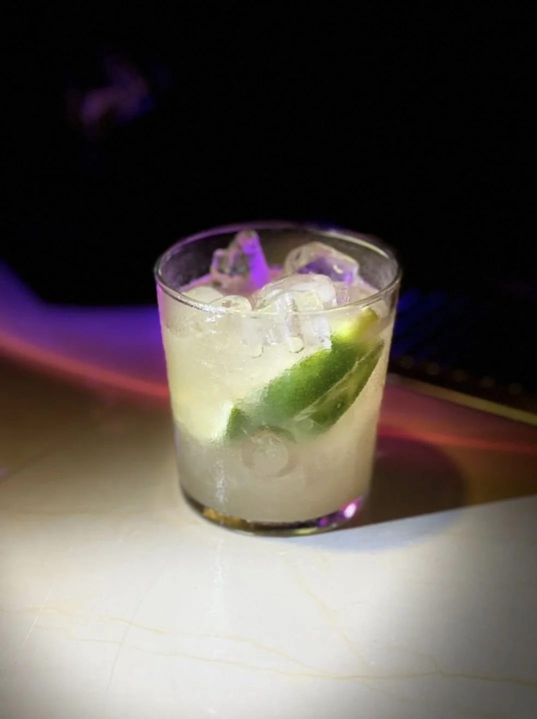 Glass of mezcal with lime wedge and ice cubes