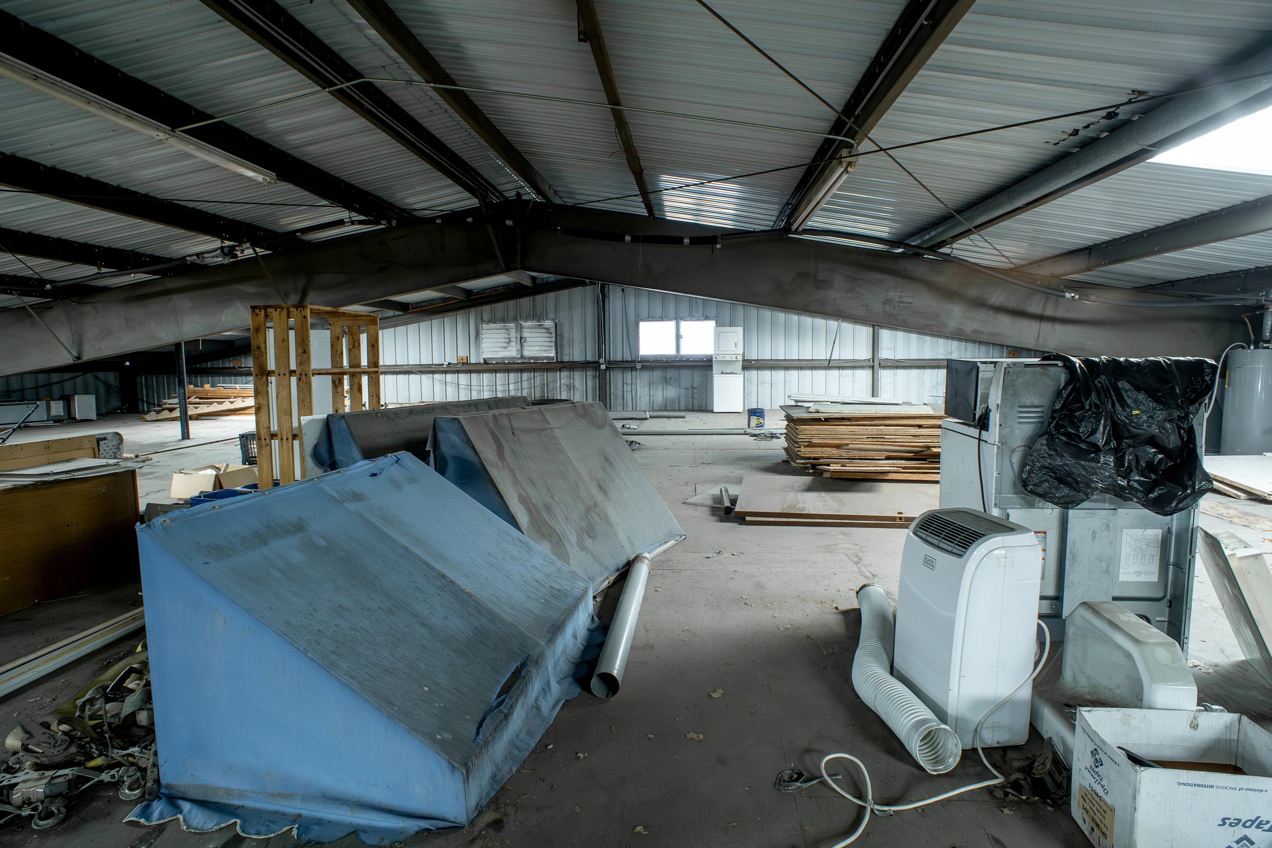 The interior of an unfinished or under-construction building with various construction materials, equipment, and debris scattered around.