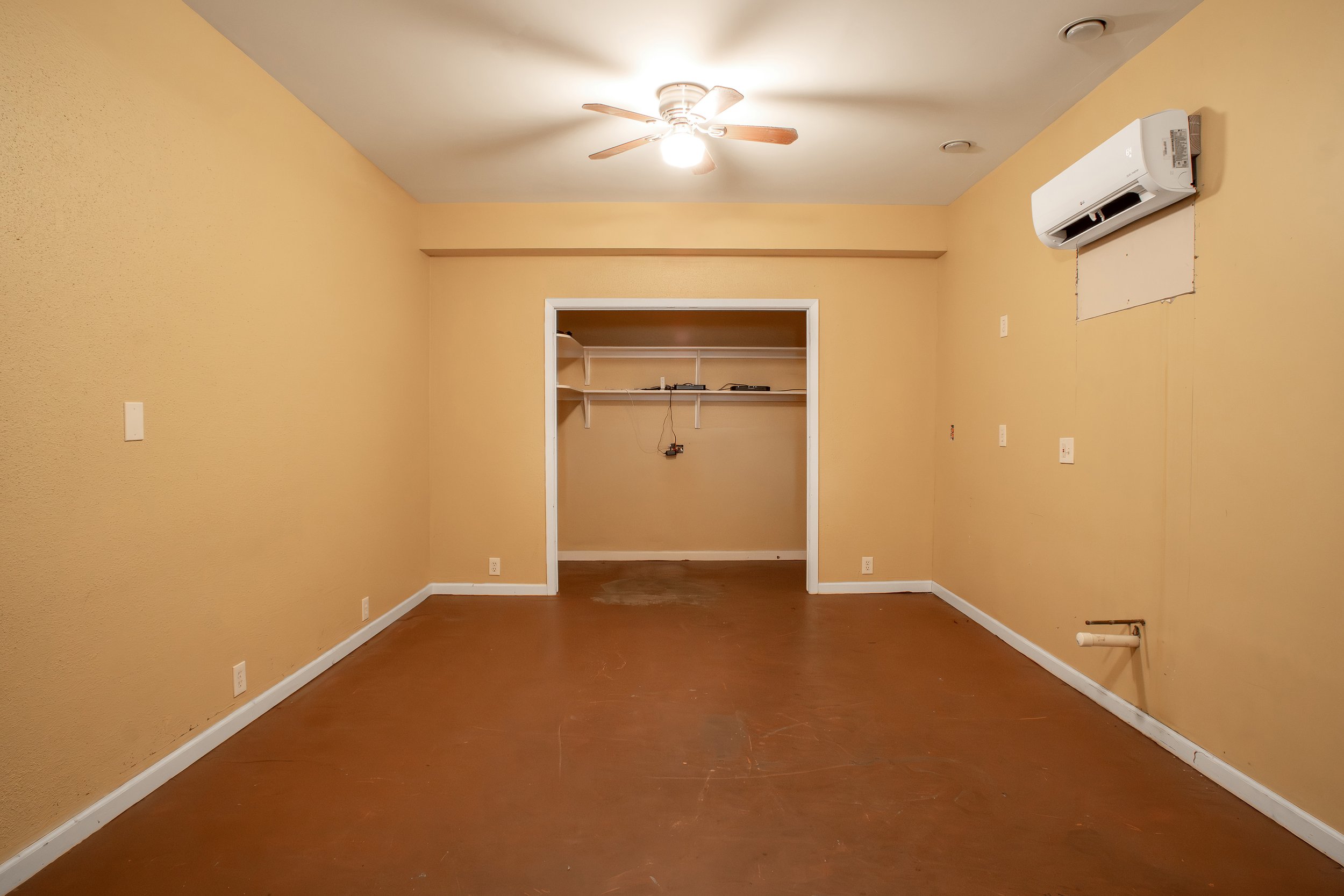 Empty room with yellow walls, hardwood floor, ceiling fan with light, air conditioning unit, and built-in closet area.