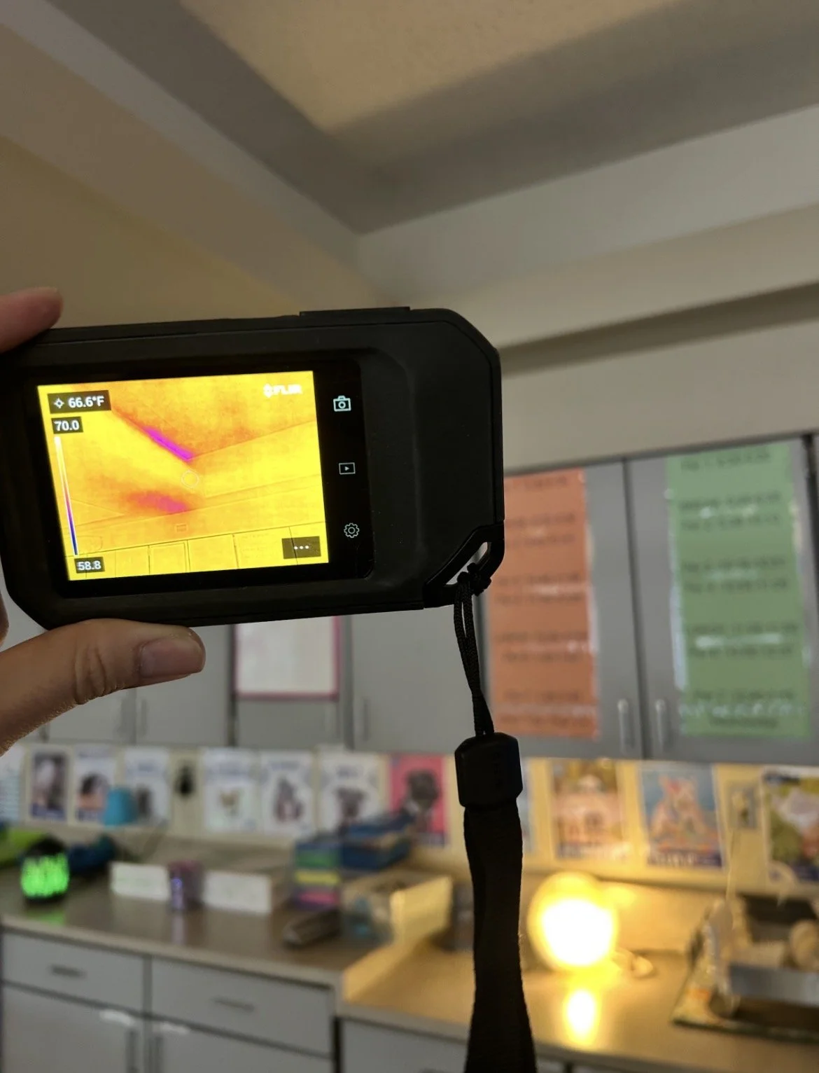 An environmental consultant performing a water intrusion/mold investigation utilizing a forward looking infrared camera in a classroom.