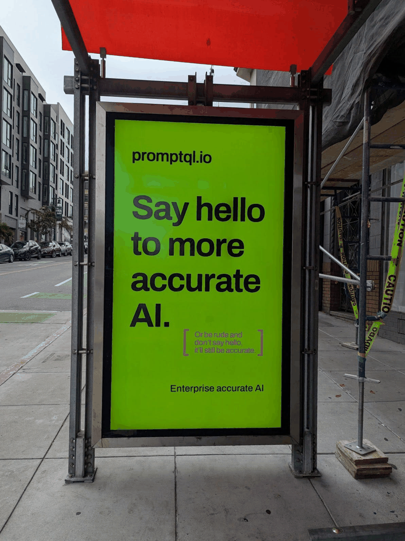 Bright green digital billboard advertising promptqi.io with the message "Say hello to more accurate AI," plus smaller text warning about rude greetings still being accurate. The sign is on a city sidewalk near a building under construction.