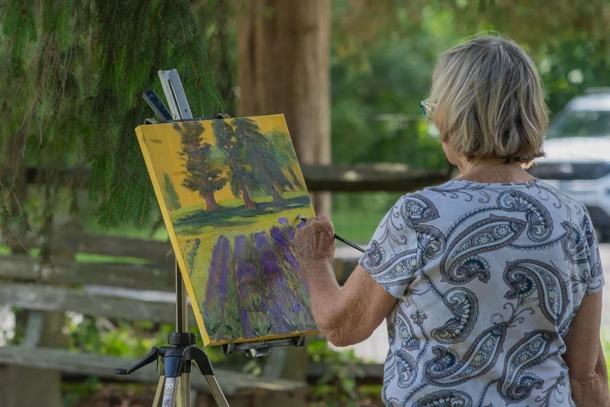 Artist painting a lavender field on an easel during a plein air session at Peace Valley Lavender Farm in Bucks County, Pennsylvania.