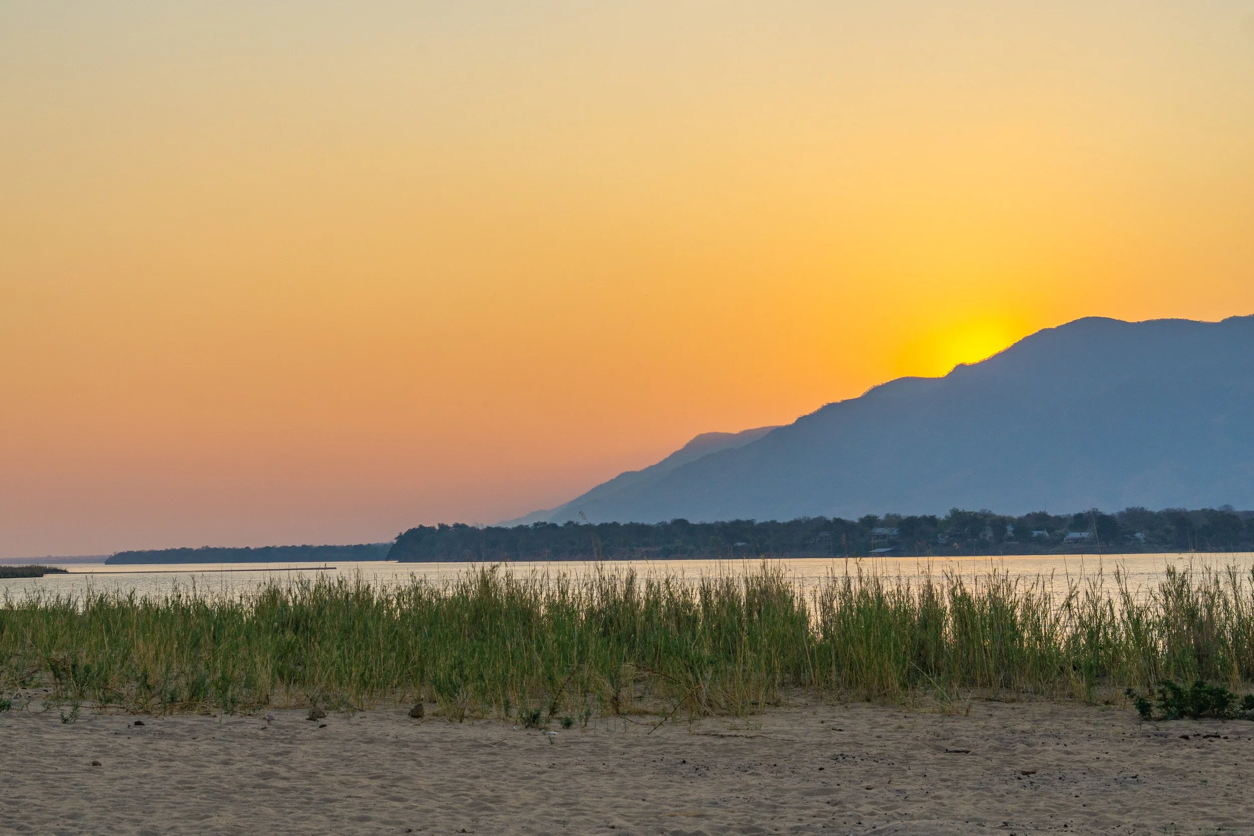 Warm sunset light fading behind the distant landscape along the Zambezi River in Africa.