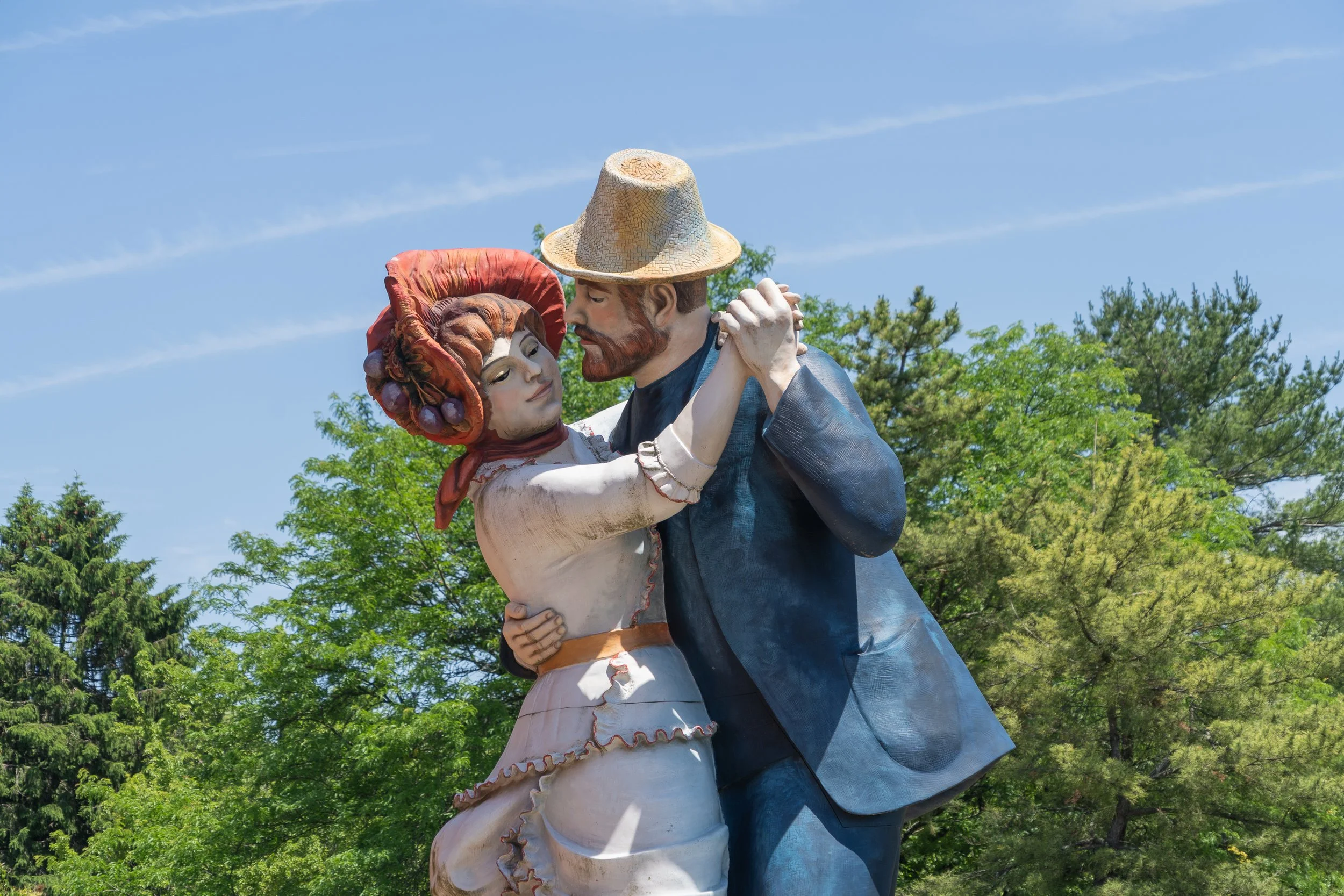 Life-sized sculpture of a dancing couple embracing beneath a blue sky at Grounds For Sculpture in Hamilton, New Jersey.