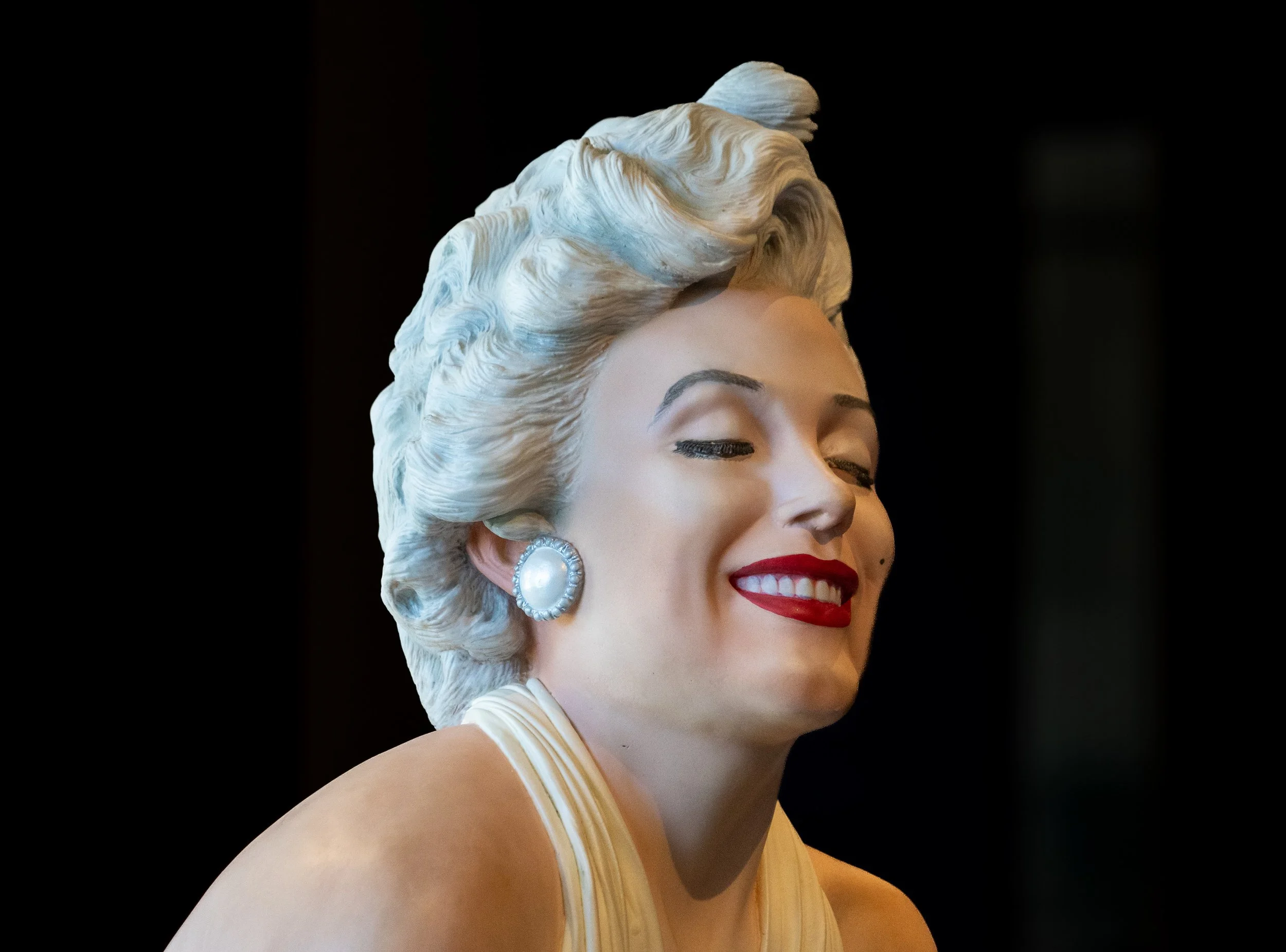 Close-up portrait of a Marilyn Monroe sculpture smiling against a dark background at Grounds For Sculpture in Hamilton, New Jersey.