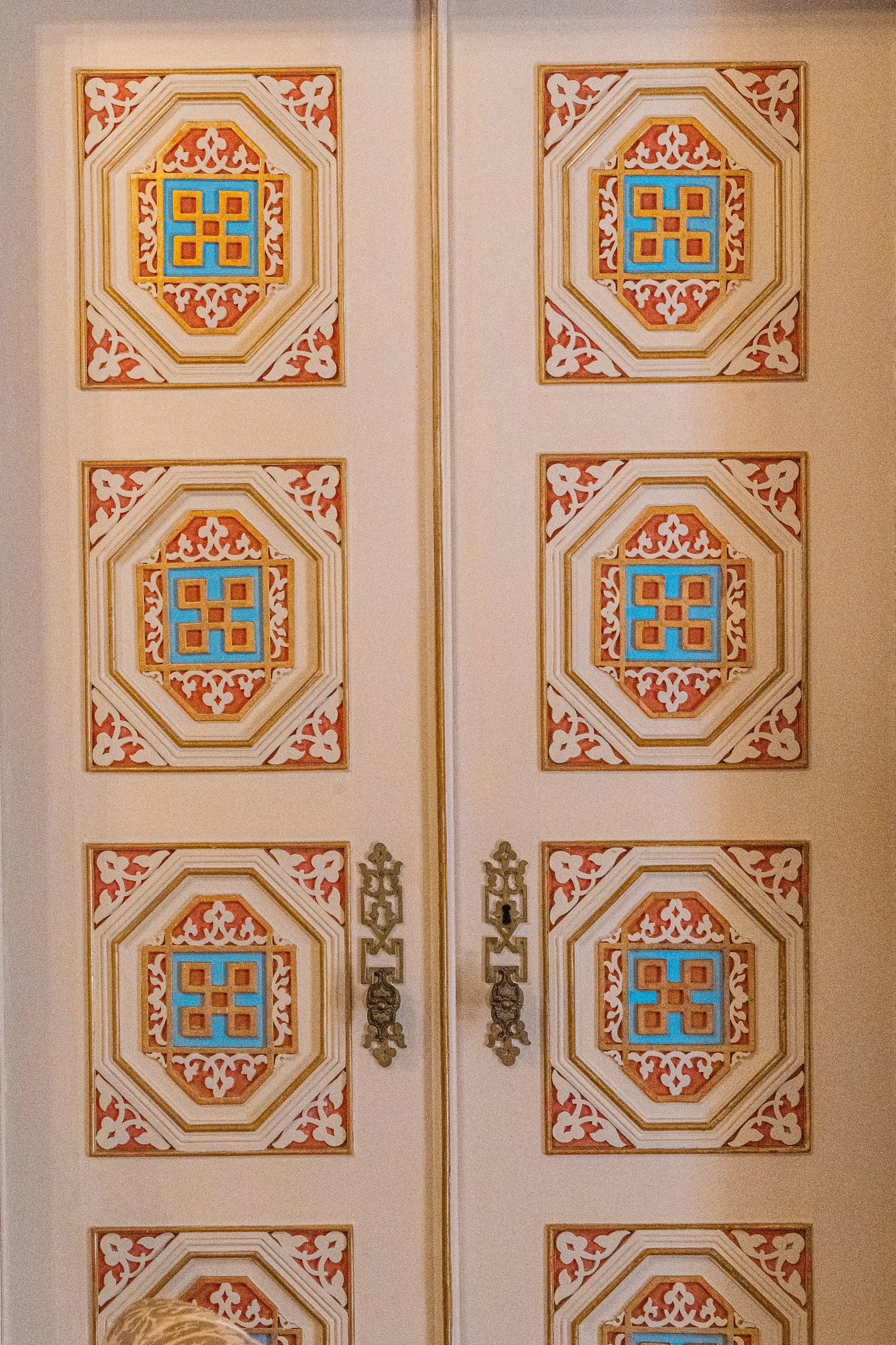 Ornately painted double doors with geometric decorative panels and intricate carved details in a historic Portuguese building.
