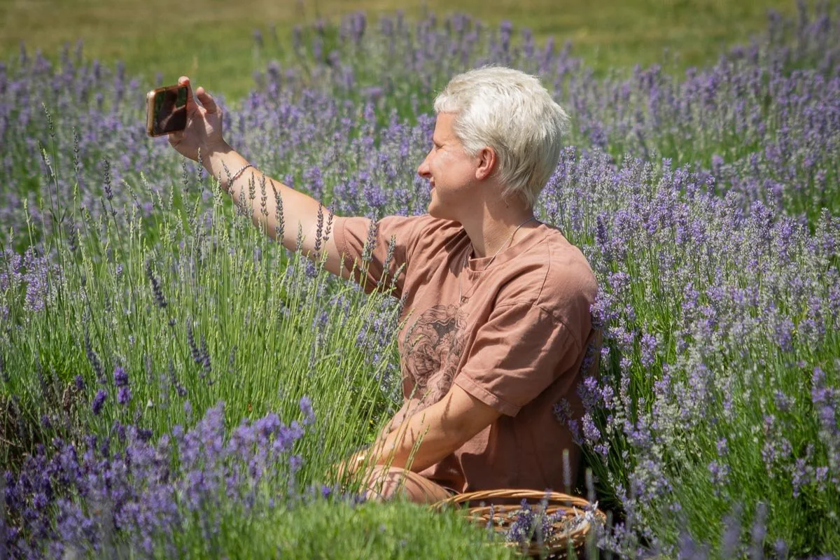 Visitor taking a selfie while seated among blooming lavender at Peace Valley Lavender Farm in Bucks County, Pennsylvania.