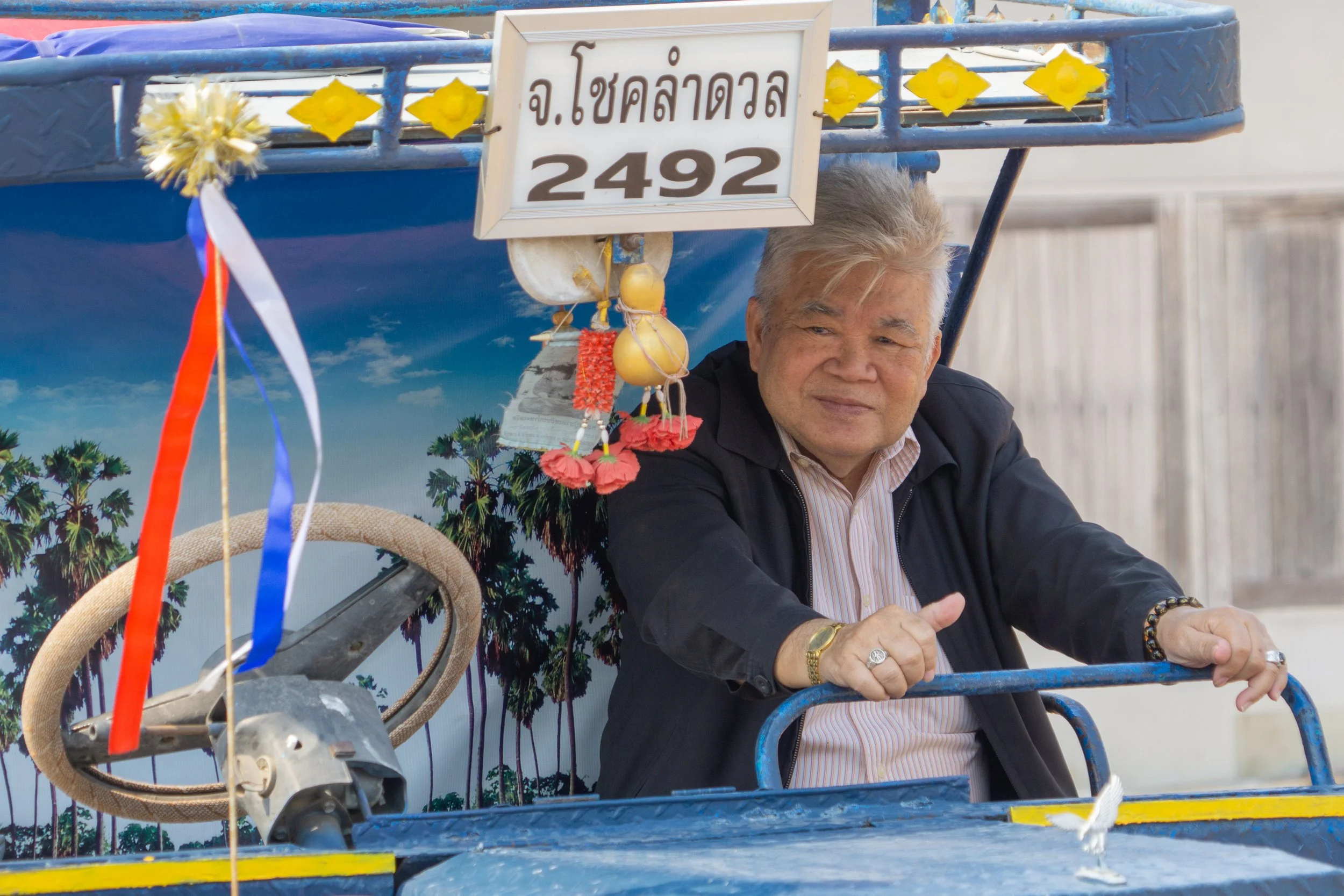 Tuk-tuk driver resting in his vehicle while waiting for passengers in Thailand.