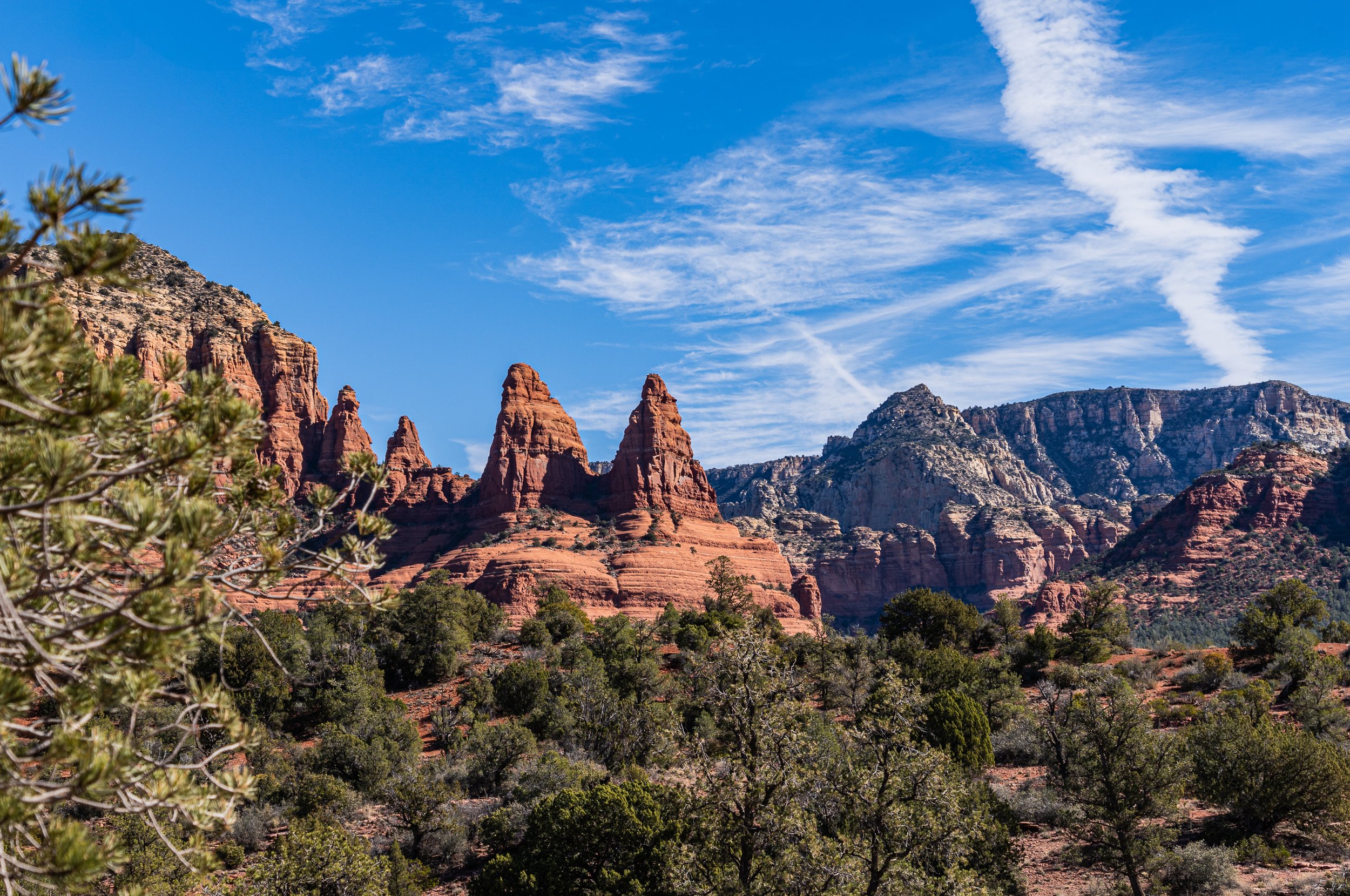 Panoramic view of Sedona's red rock mesas and buttes rising above juniper woodland beneath a clear blue Arizona sky.