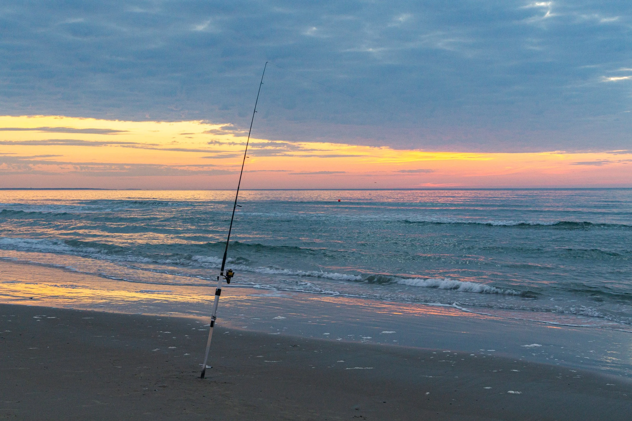 A fishing rod planted in the sand during sunrise on Ogunquit Beach