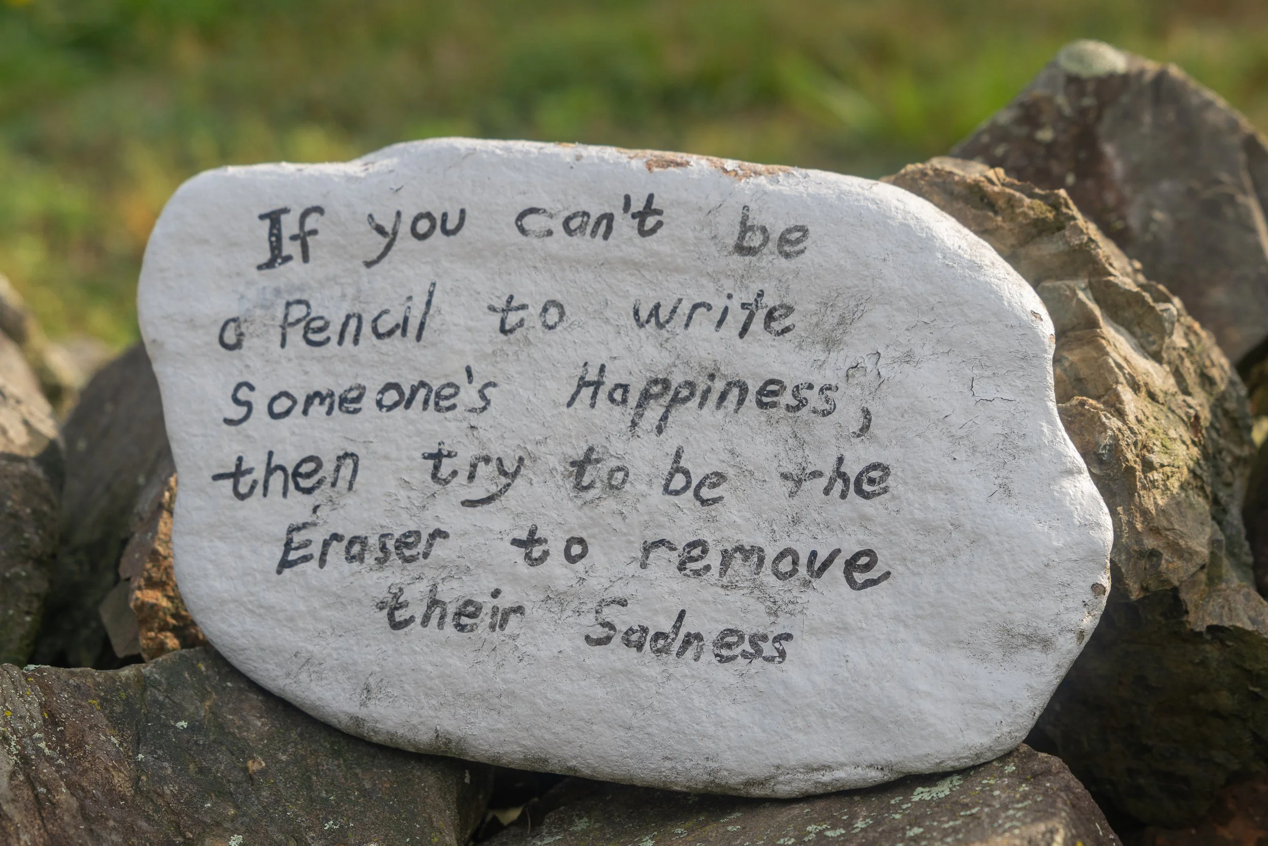 Painted stone encouraging people to write happiness instead of erasing sadness