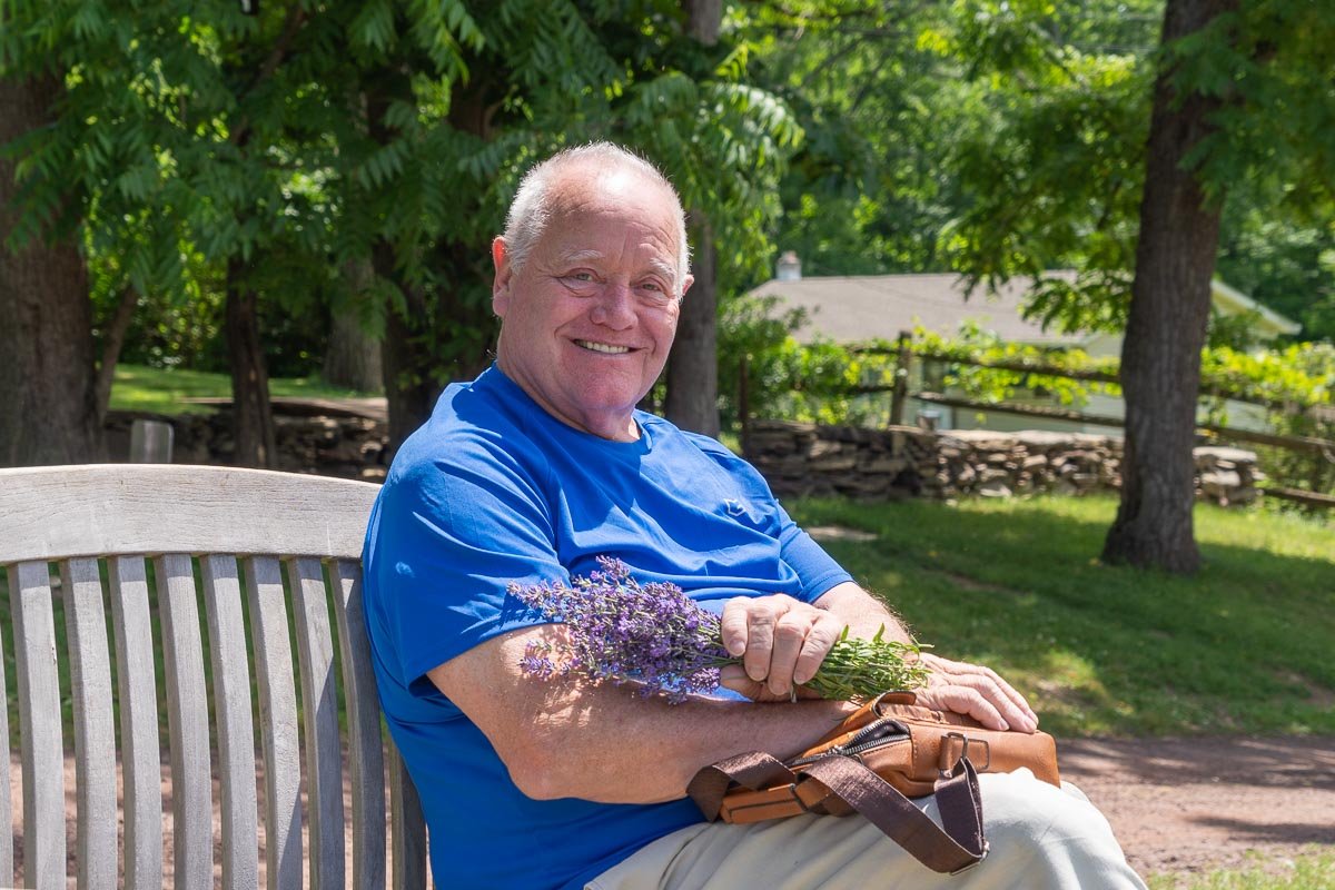 Visitor relaxing on a bench while holding a freshly cut bouquet of lavender at Peace Valley Lavender Farm in Bucks County, Pennsylvania.