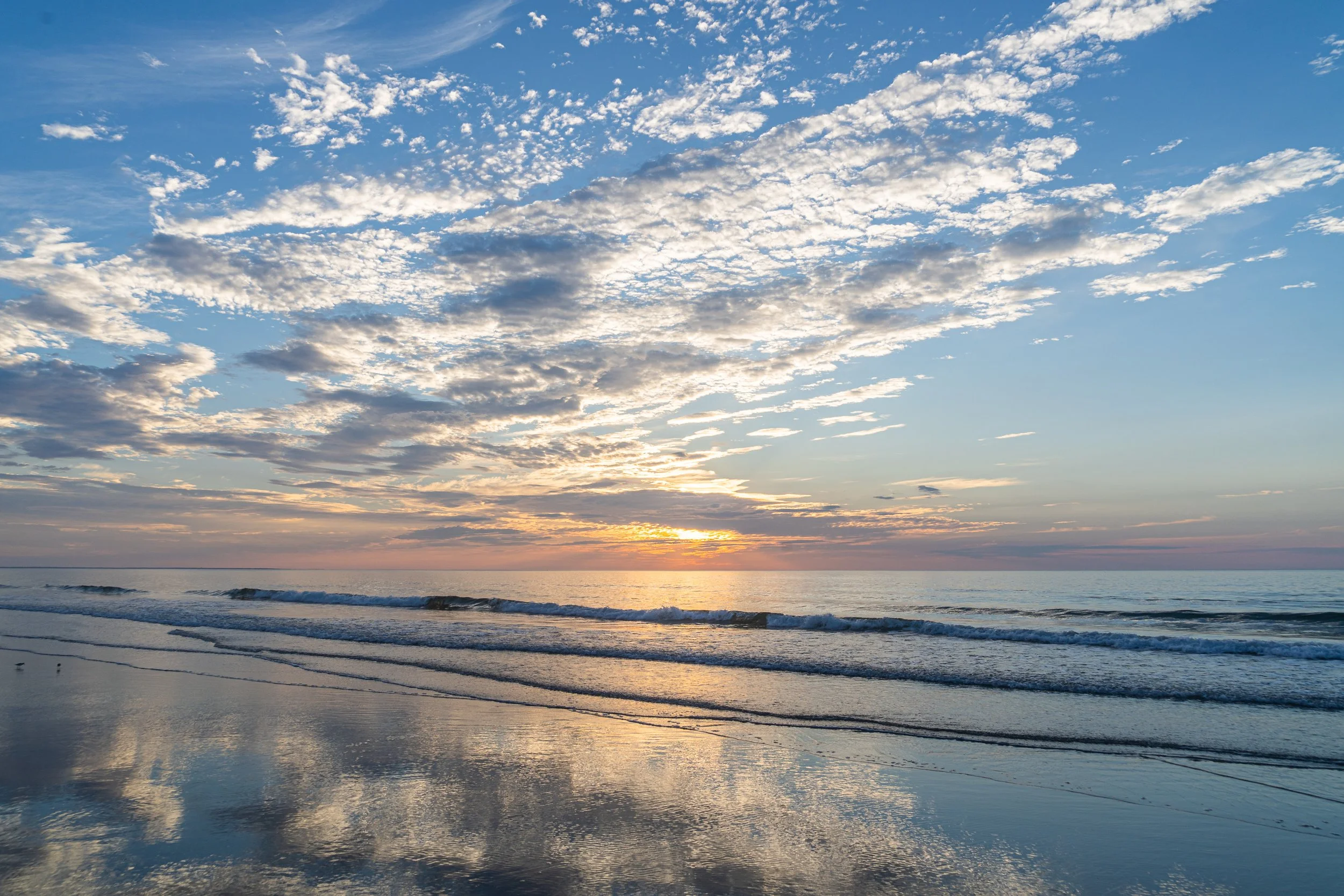 Colorful clouds and reflections stretching across the wet sand at sunrise in Ogunquit