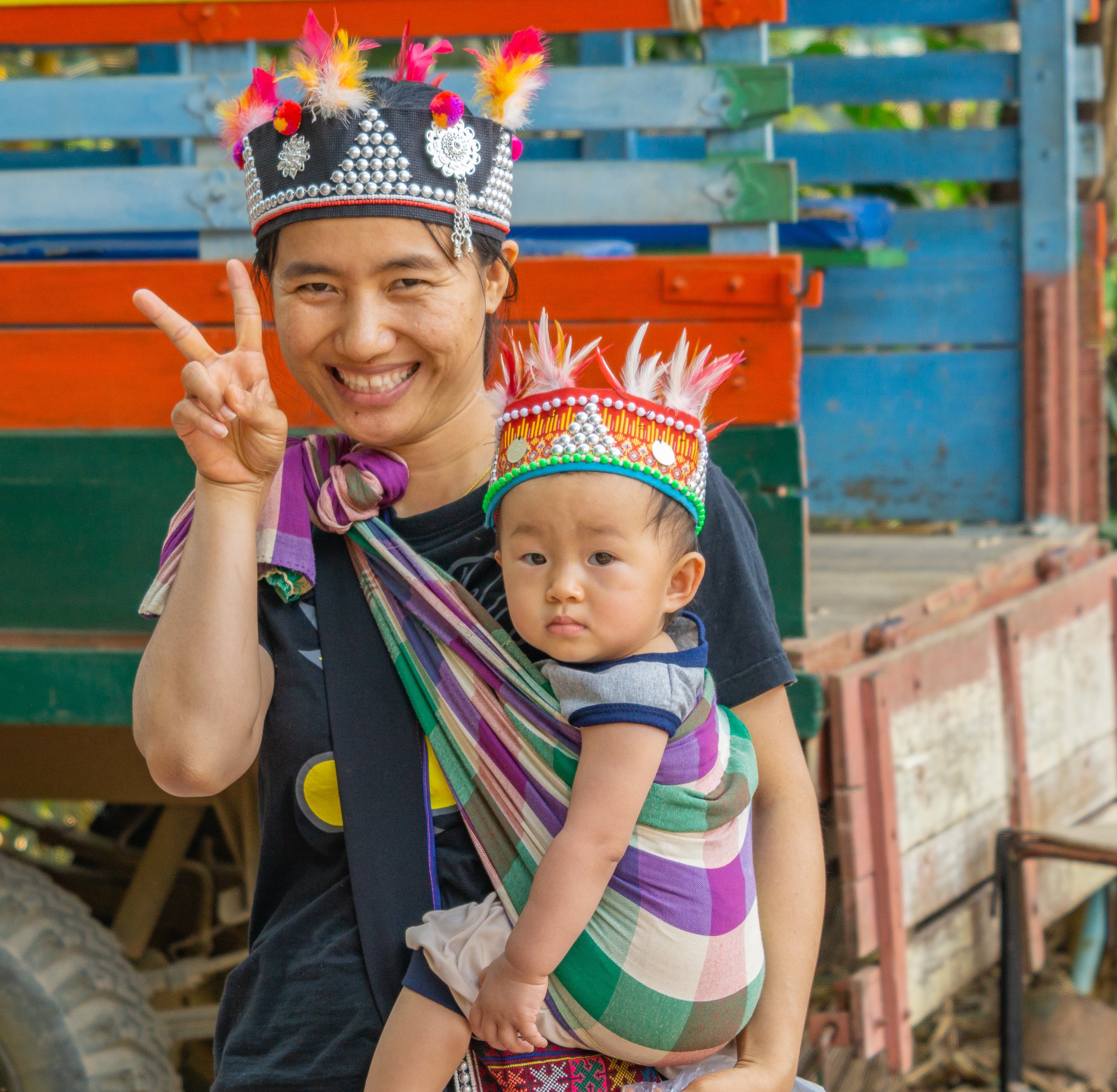 Mother carrying her young child while wearing traditional clothing in northern Thailand.