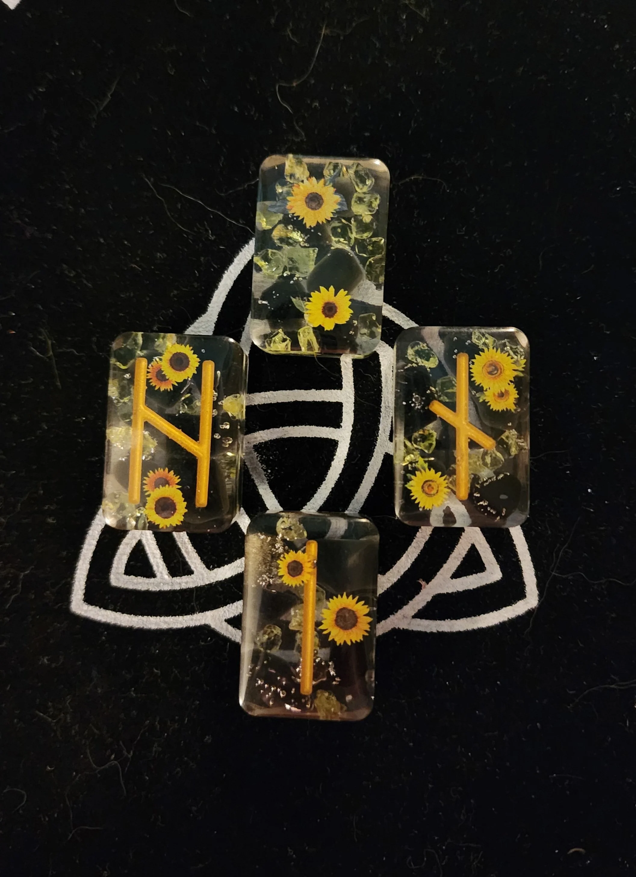 A tic-tac-toe game made of clear ice blocks with embedded sunflowers and small rocks, on a black background with a white geometric design.