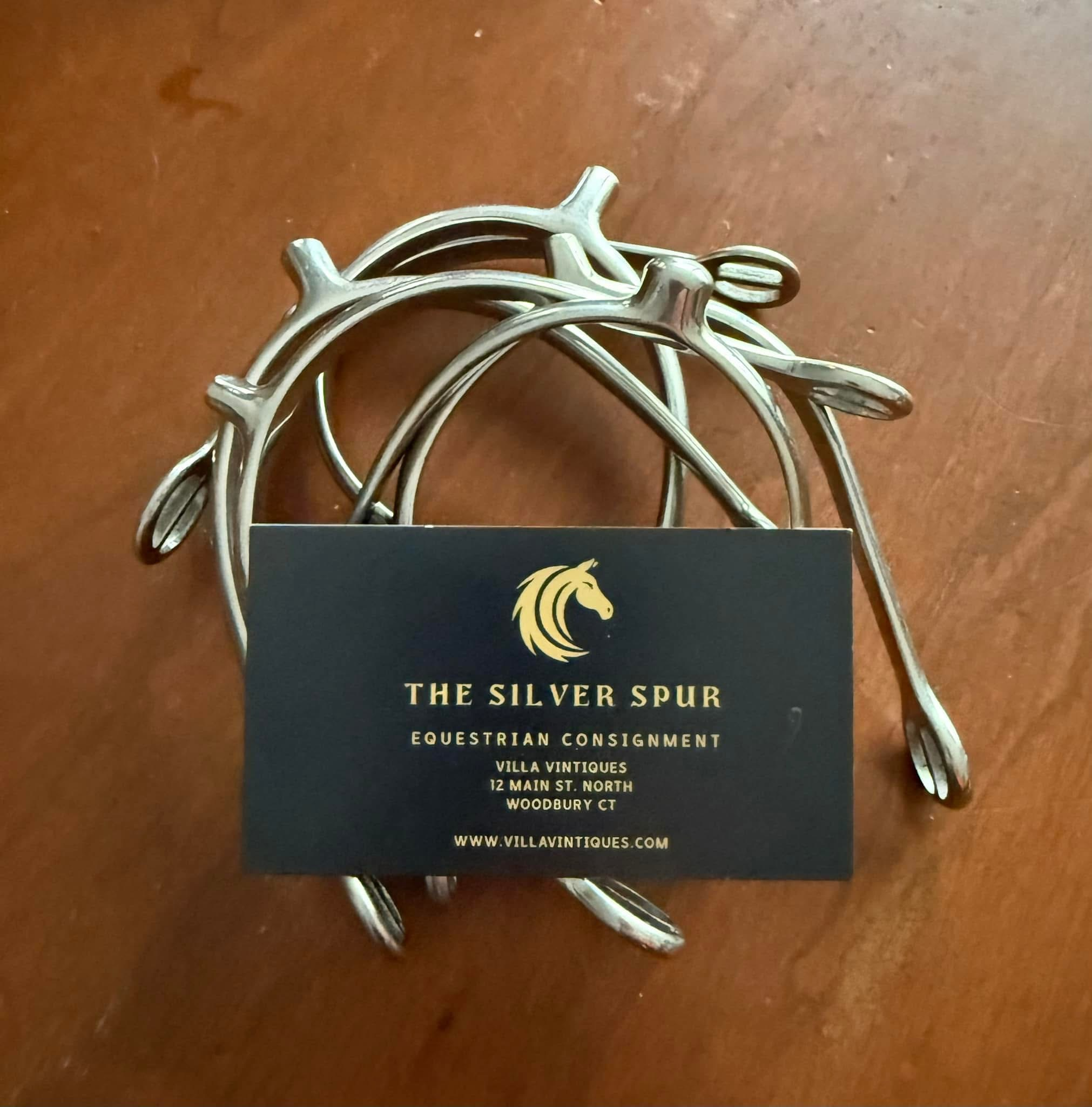 The Silver Spur Equestrian Consignment at Villa Vintiques business card sitting on a pair of silver spurs.