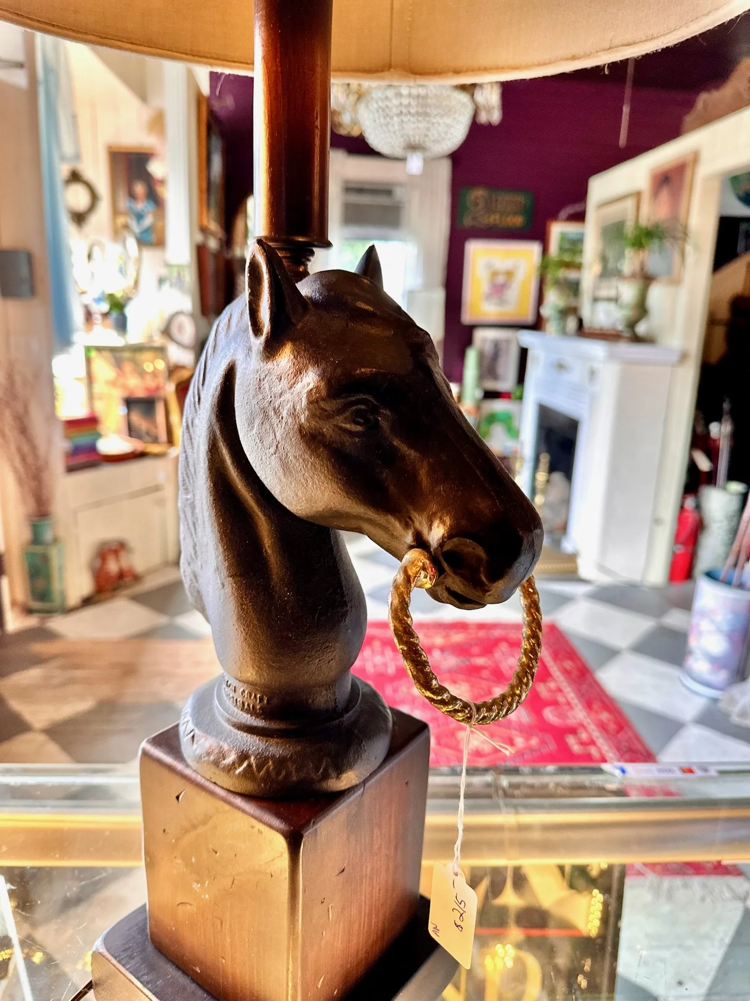 Inside Villa Vintiques, a carved wooden horse head with a gold ring in its mouth, mounted on a wooden stand in a room with colorful artwork and furniture.