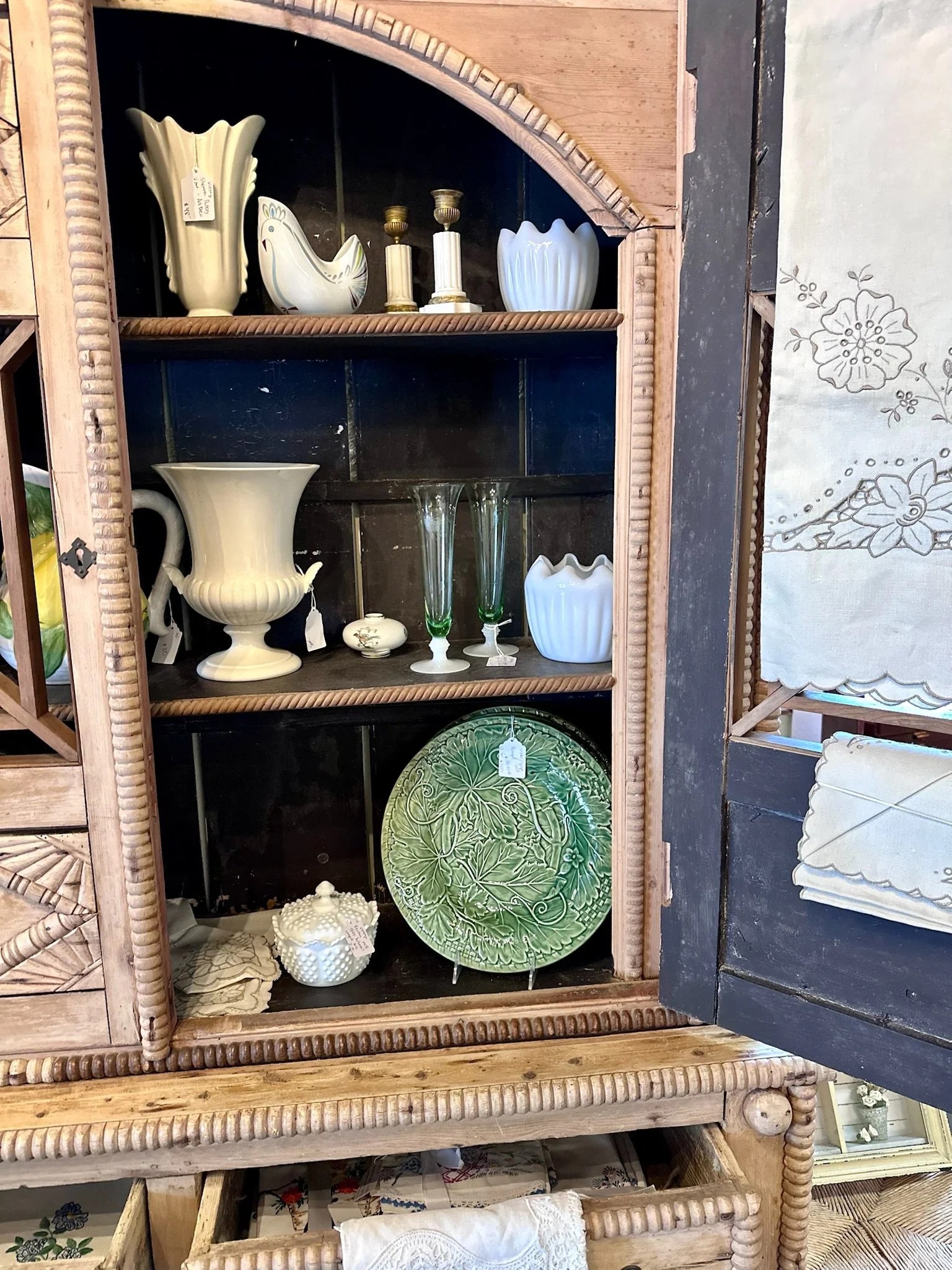 Antique Irish Pine Housekeeper’s Cabinet for sale at Villa Vintiques. A display cabinet with various ceramic vases, plates, and decorative items inside. The cabinet has a wooden frame with glass doors.
