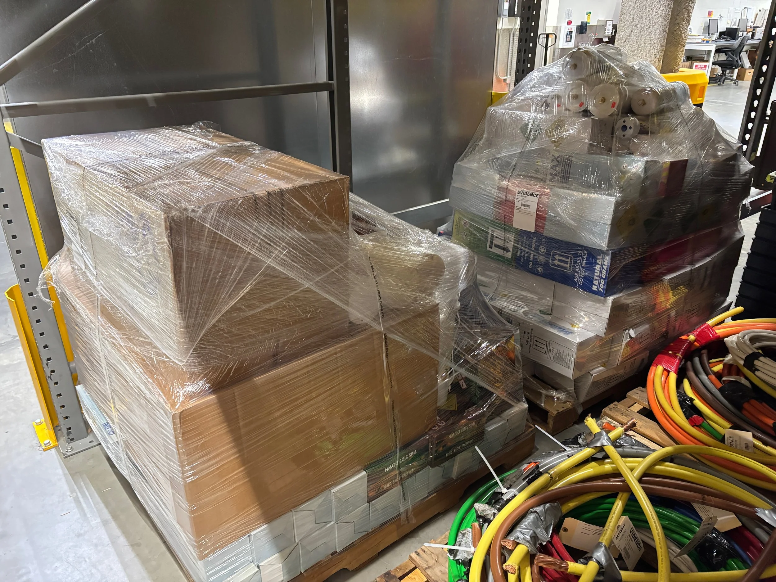 Shrink-wrapped pallets of government surplus and evidence items staged for asset management and auction at the TiDDRs warehouse.