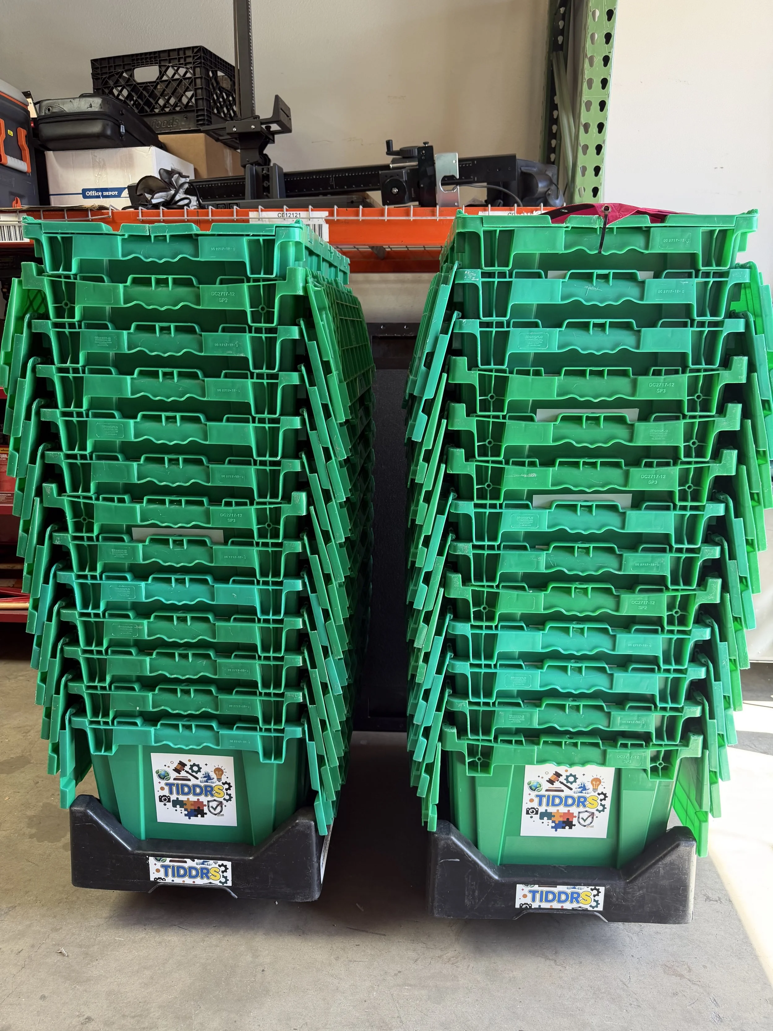 Two stacks of green TiDDRs-branded storage totes secured to wheeled bases, prepped for transport and inventory deployment.