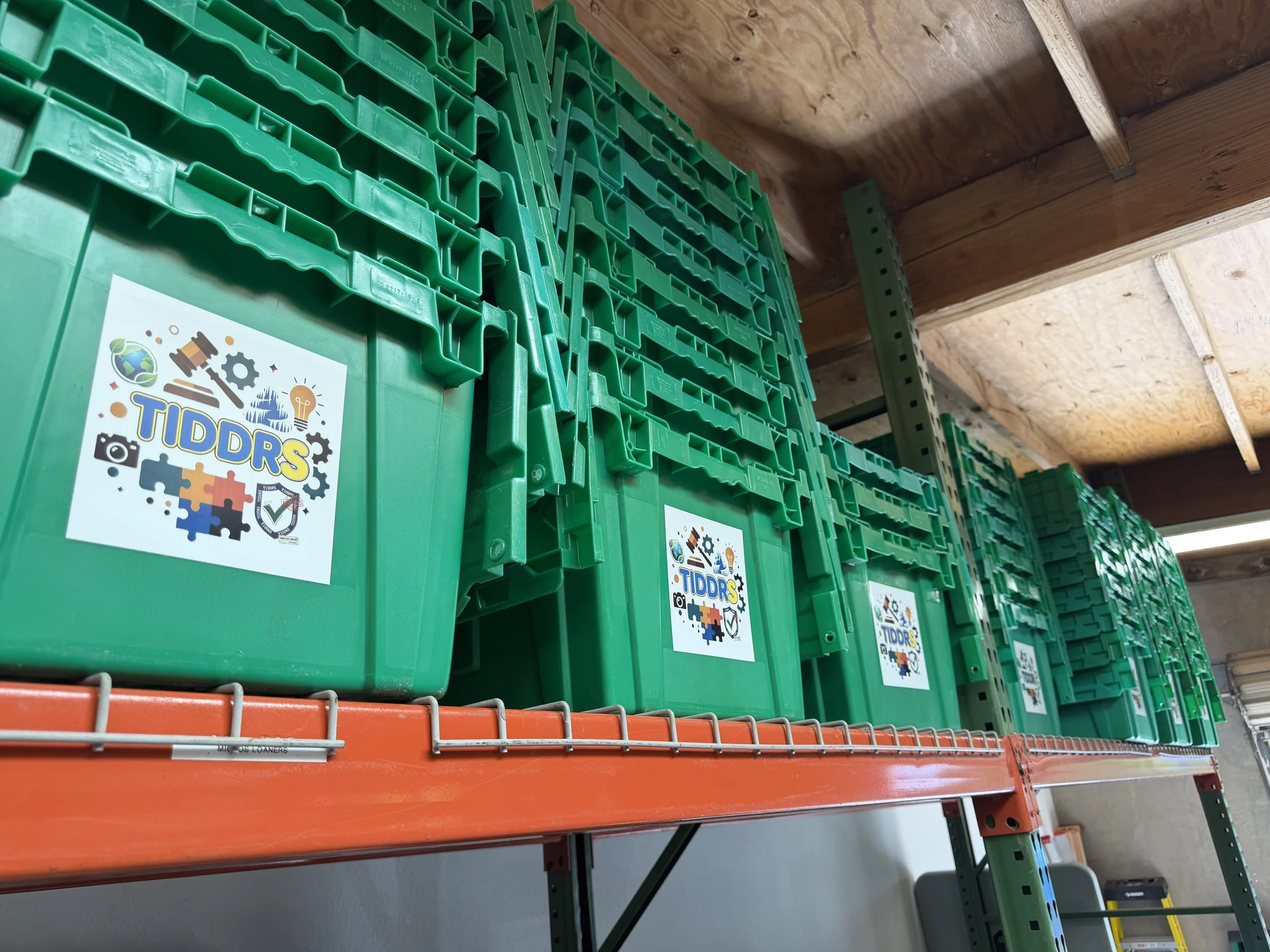 Rows of TiDDRs-branded green storage totes stored on industrial pallet racking in the warehouse, ready for asset management projects.