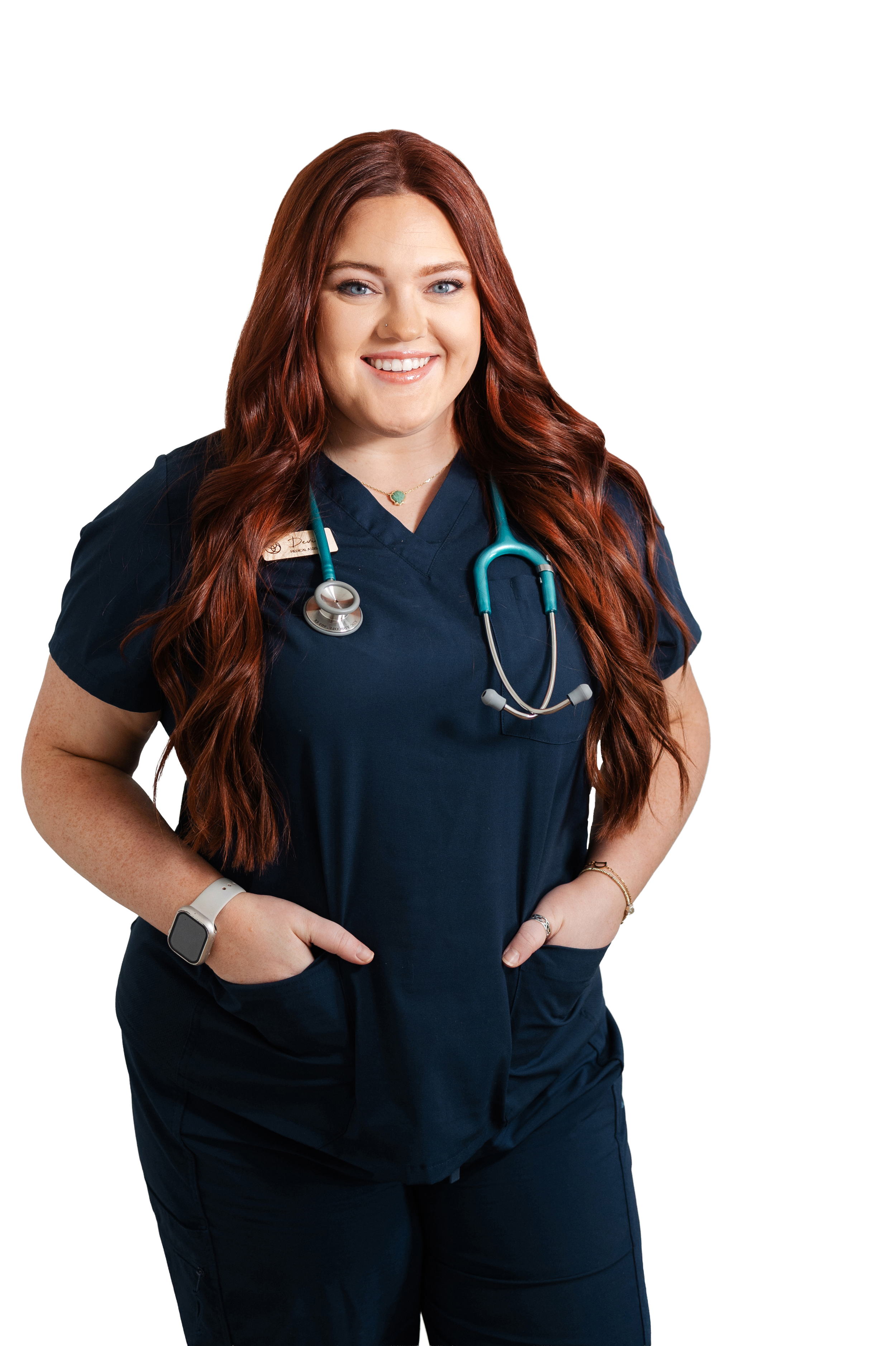 Devin Taubert | Smiling woman with long red hair, wearing navy medical scrubs and stethoscope.