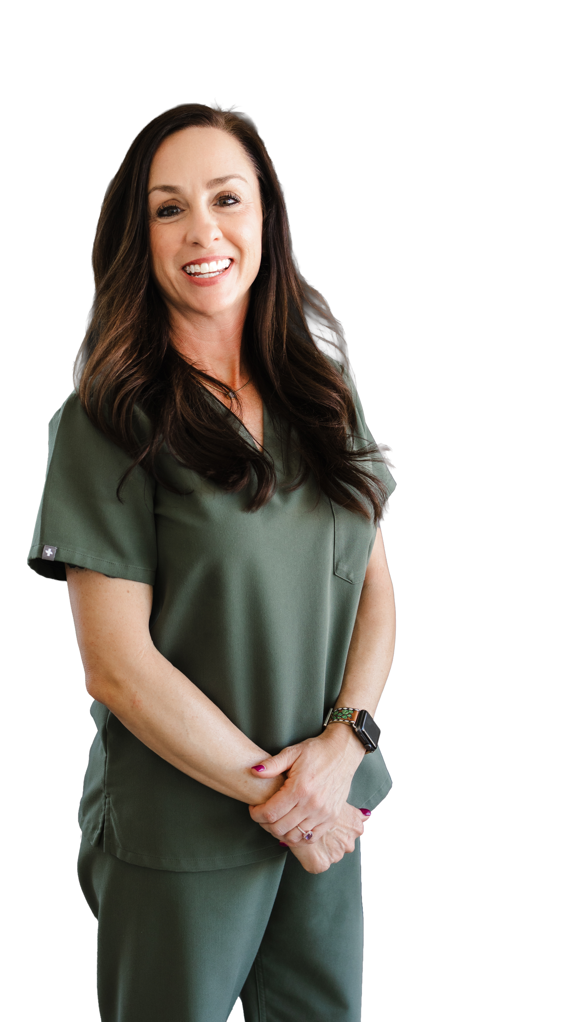 TIFFANY PETERS | A woman with long dark hair wearing green medical scrubs and a smartwatch, smiling and standing with hands crossed in front.