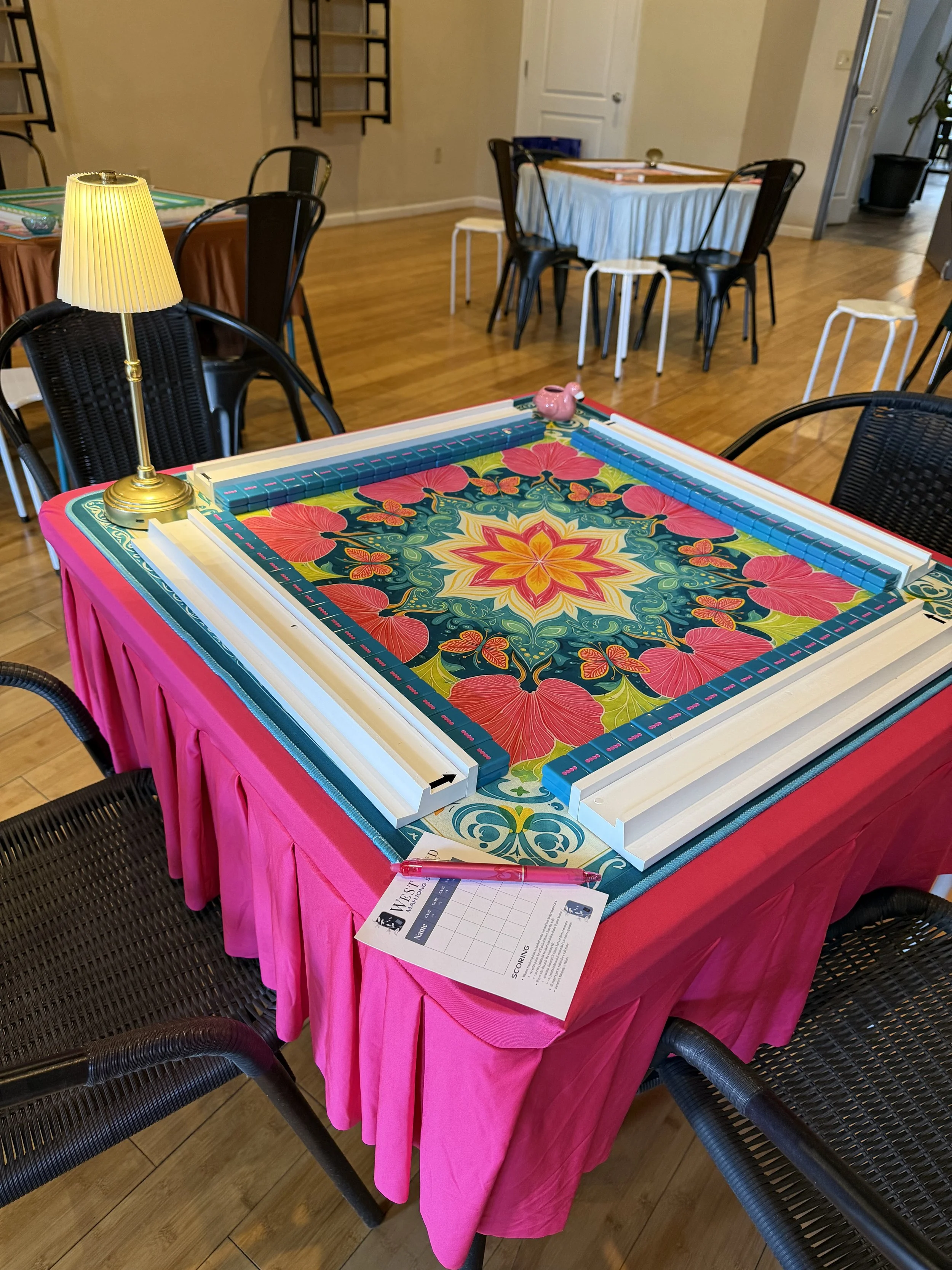 A room of mahjong tables set and ready, tiles racked and score sheets laid out