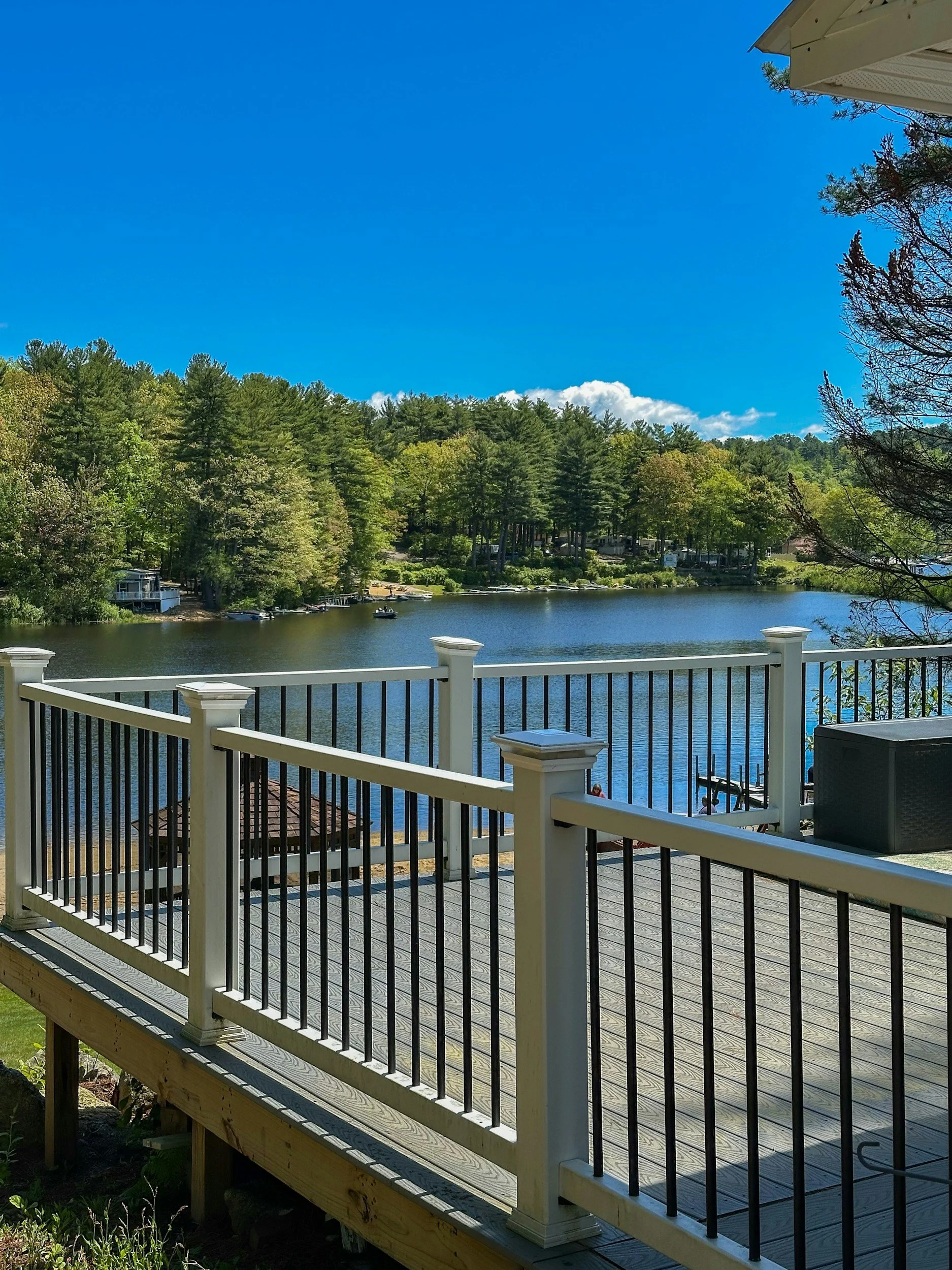 Waterfront composite deck with a white Trex Transcend railing with black aluminum balusters overlooking a lake with boats.