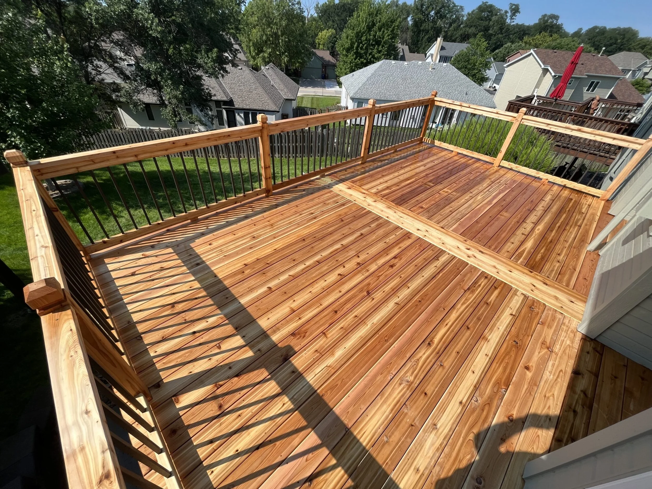 Pressure-treated wood deck with a wood cocktail railing and black aluminum balusters.