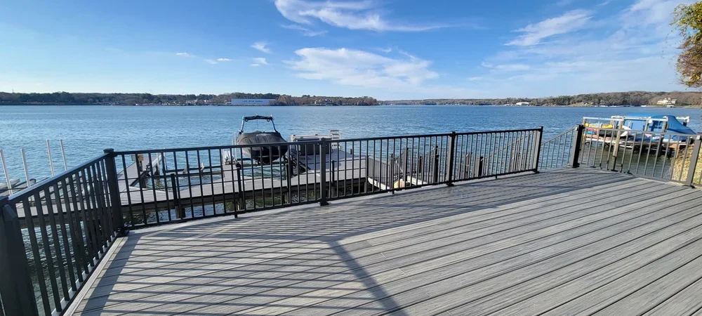 Lakeside PVC deck with black Trex Signature railing overlooking a dock and waterfront, perfect for wet and sunny environments.