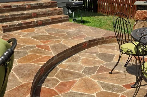 Stamped concrete patio with curved steps and natural stone pattern, creating a durable and decorative outdoor living space.