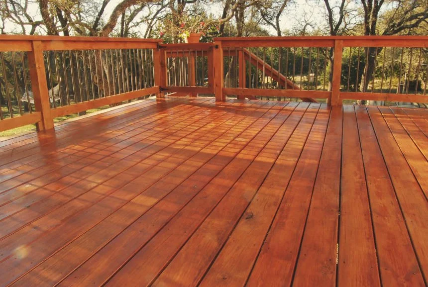wood deck with a cocktail railing, bronze balusters and gate to stairs. stained in a rich cedar color
