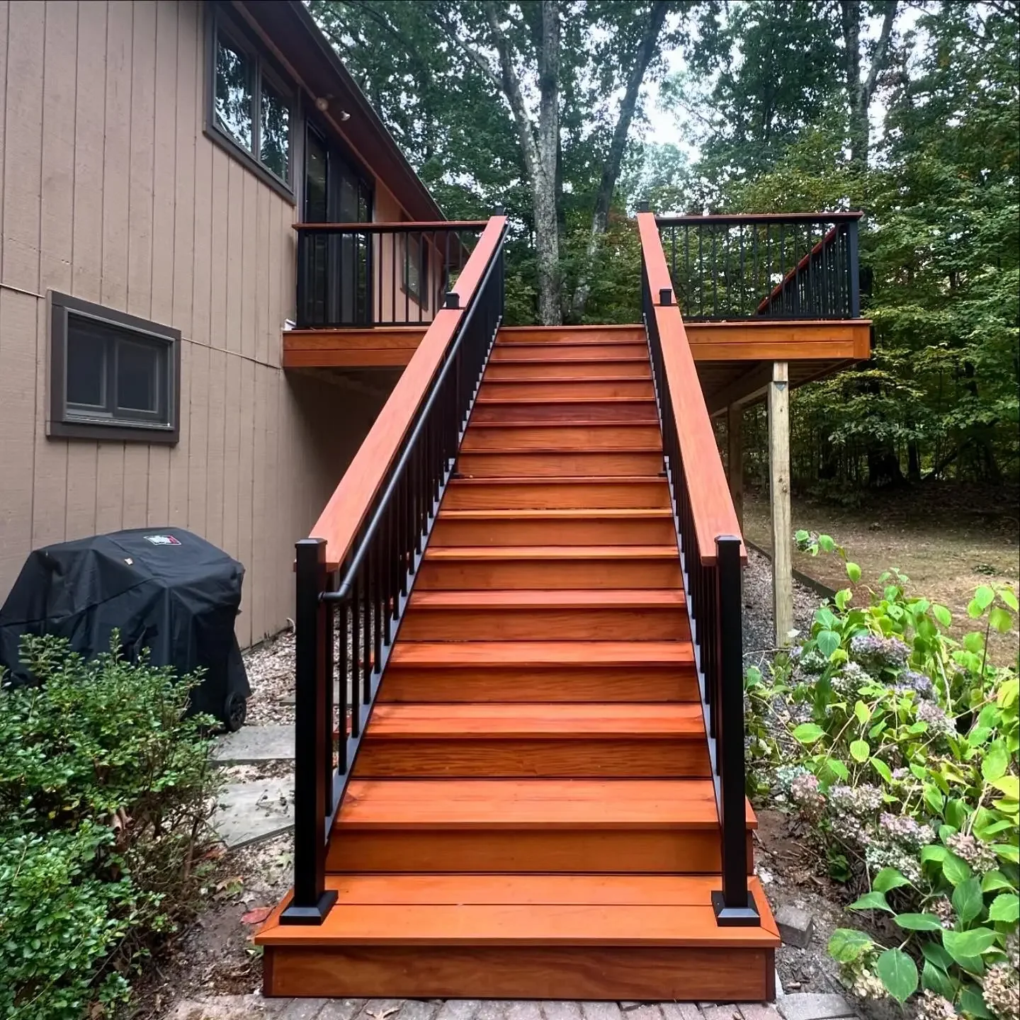 second story wood deck beautifully stained with black cocktail railing and a long staircase