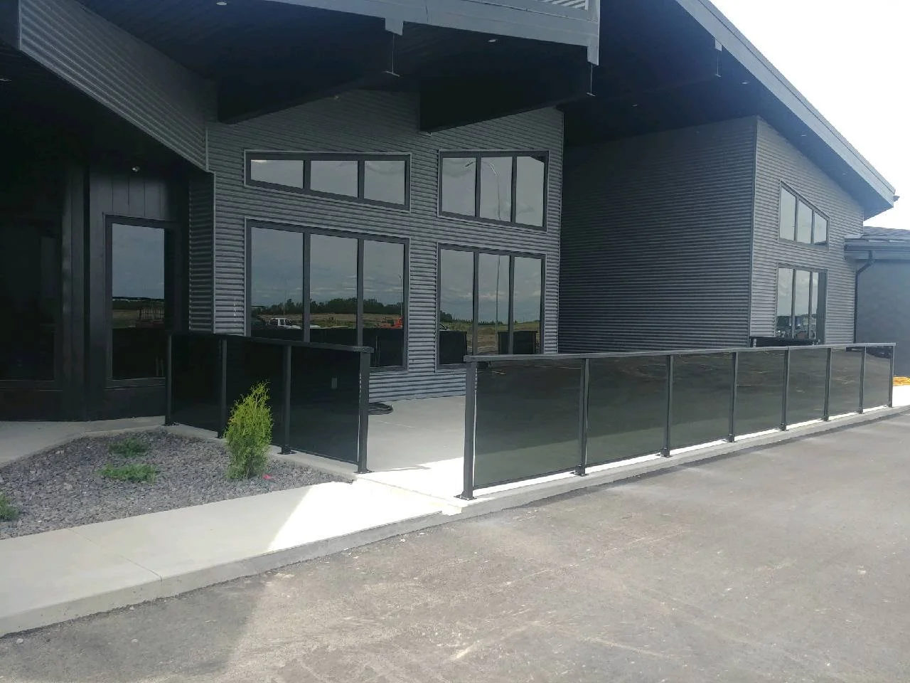 Exterior view of a modern building with large windows, black metal railings, and a curved roof design.