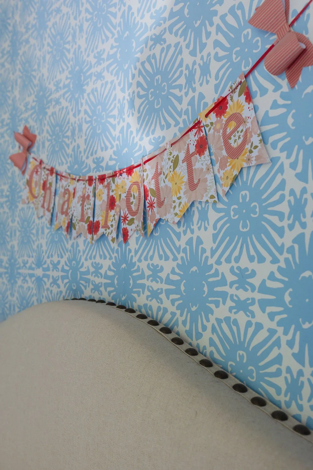 Decorative banner with the word 'LOVE' hanging on a red ribbon against a blue and white patterned wall.