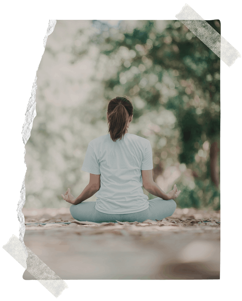 A woman meditating on the ground outside facing away | Northwest Wellness | Therapy & Consulting in Thunder Bay