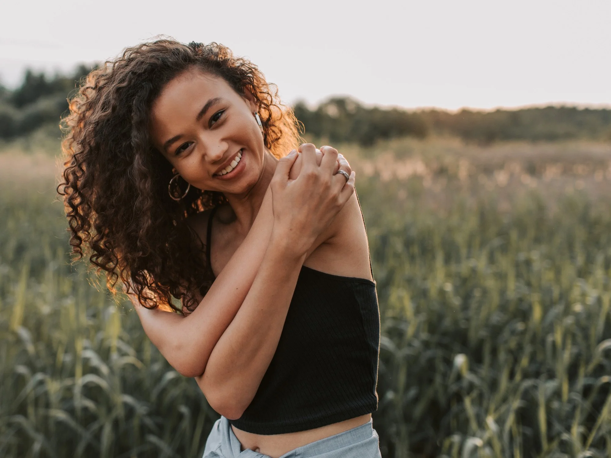 A happy girl hugging herself in a field