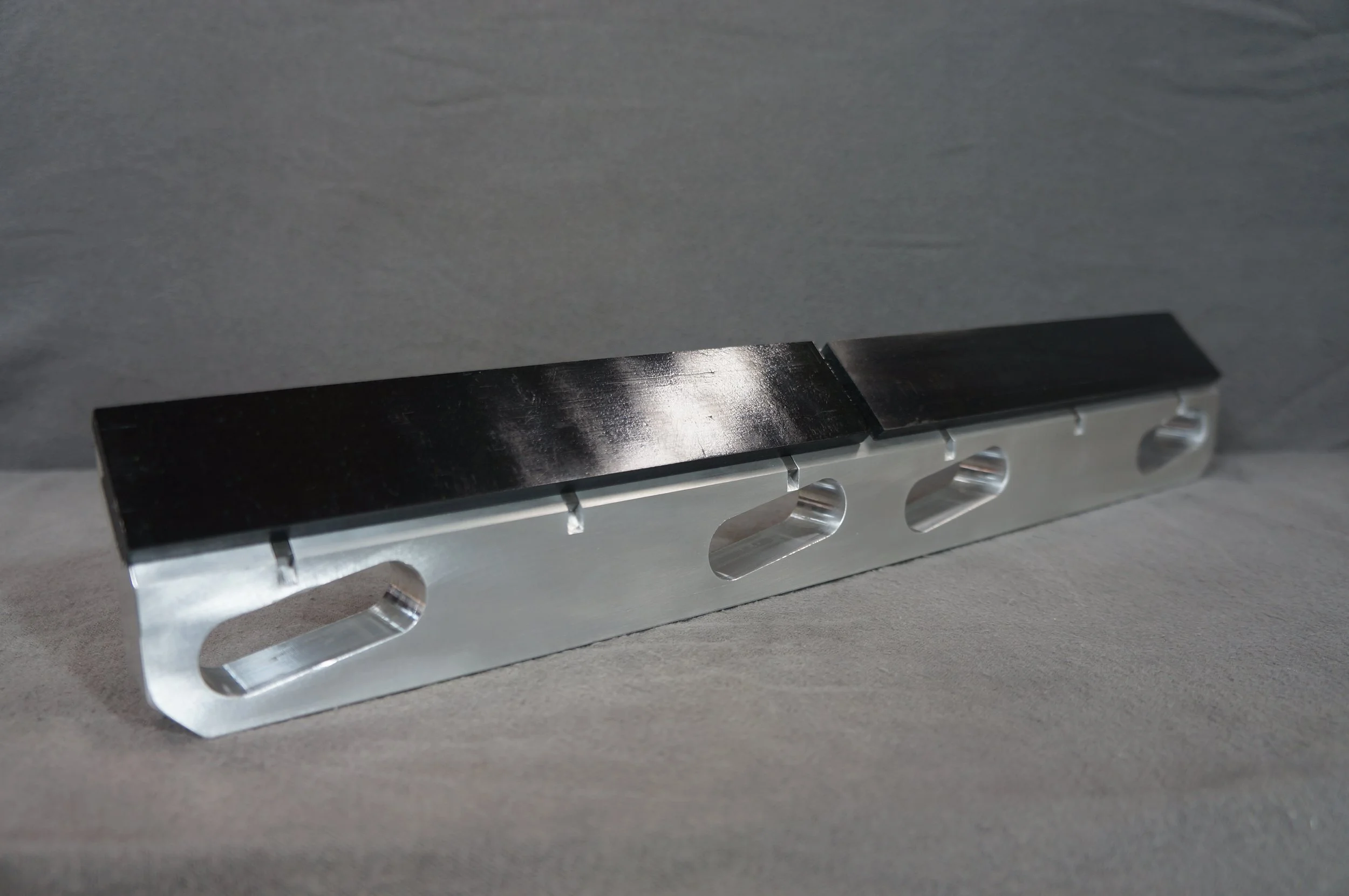 Close-up of a metallic object with a black top part and silver base, placed on a gray surface.