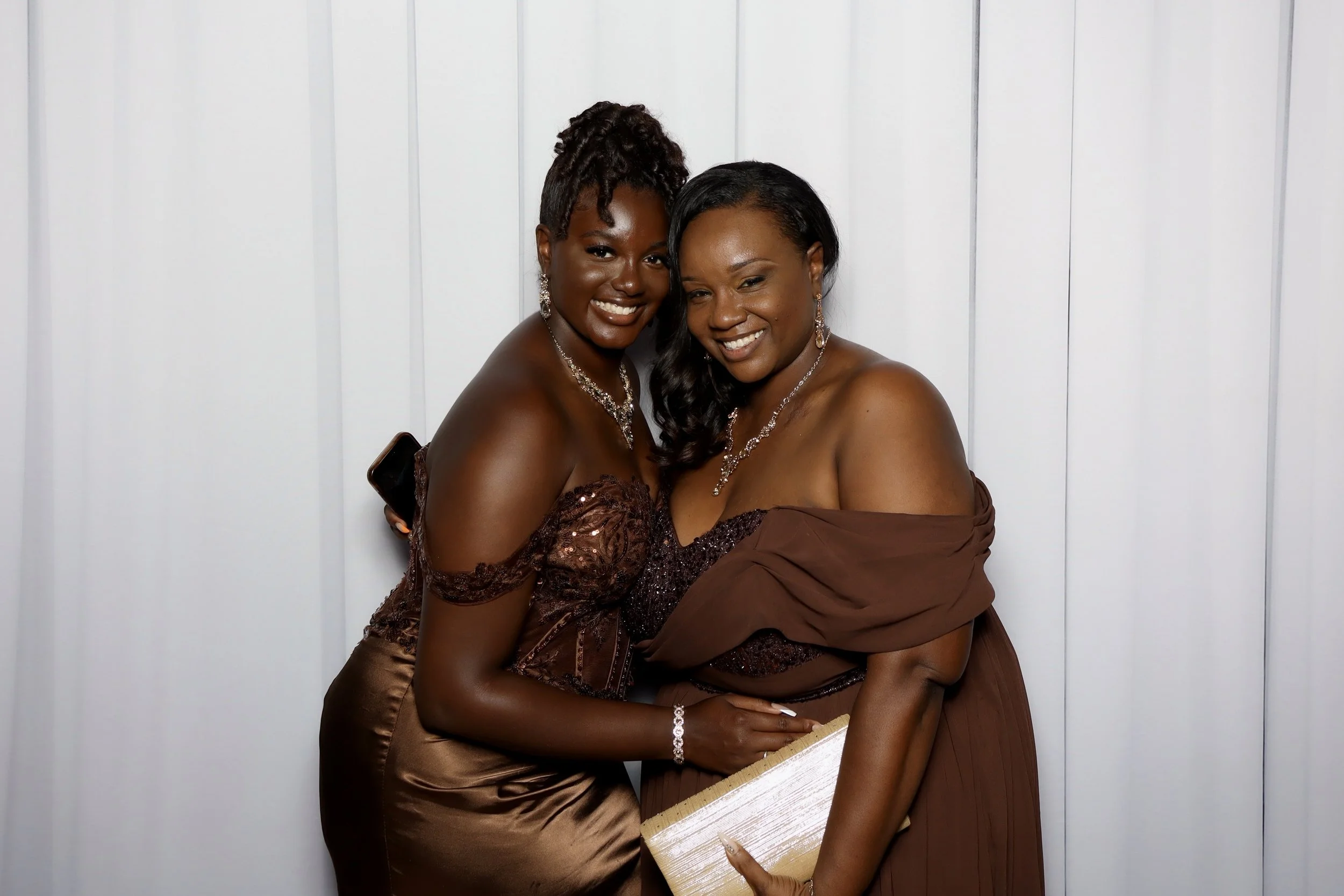 2 women dressed formal smiling and posing for a picture.