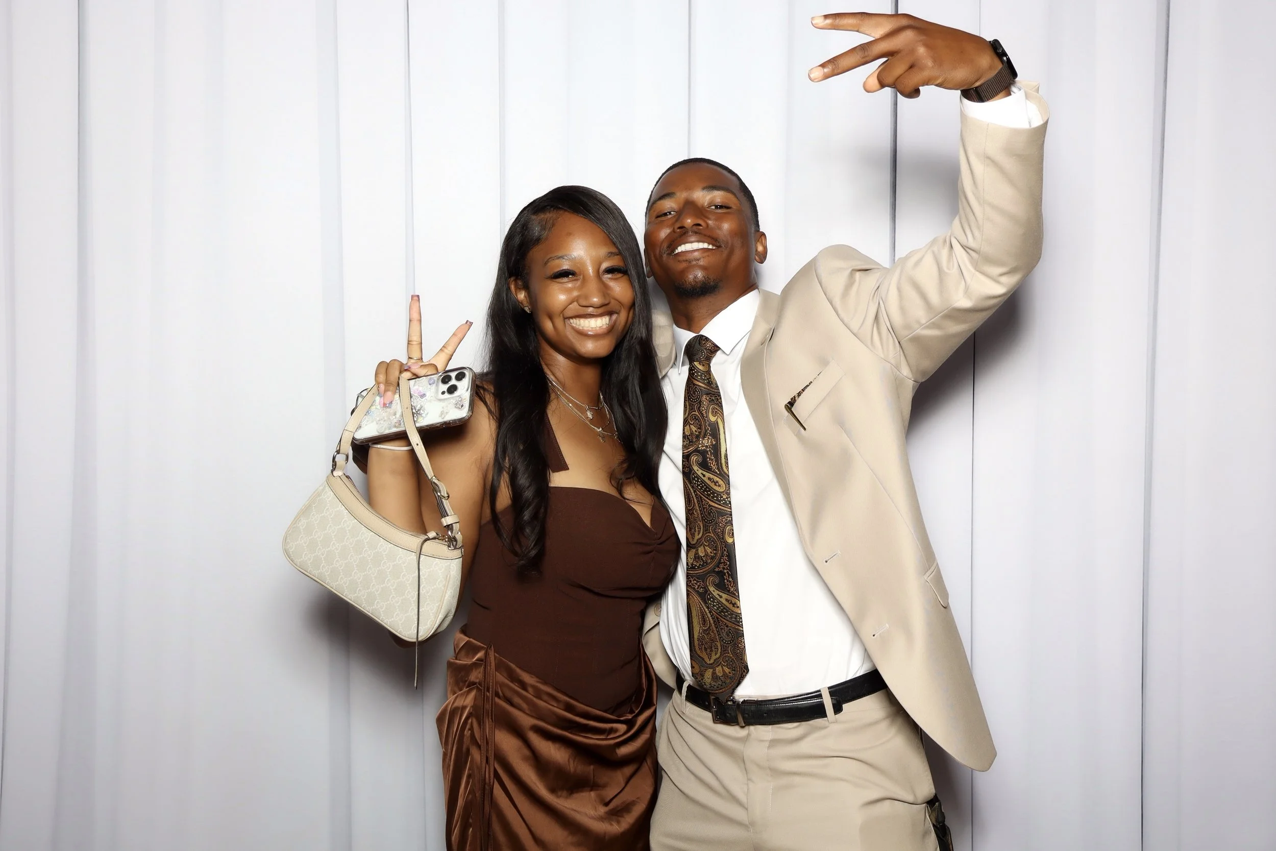 2 party goers posing infant of a nice wall