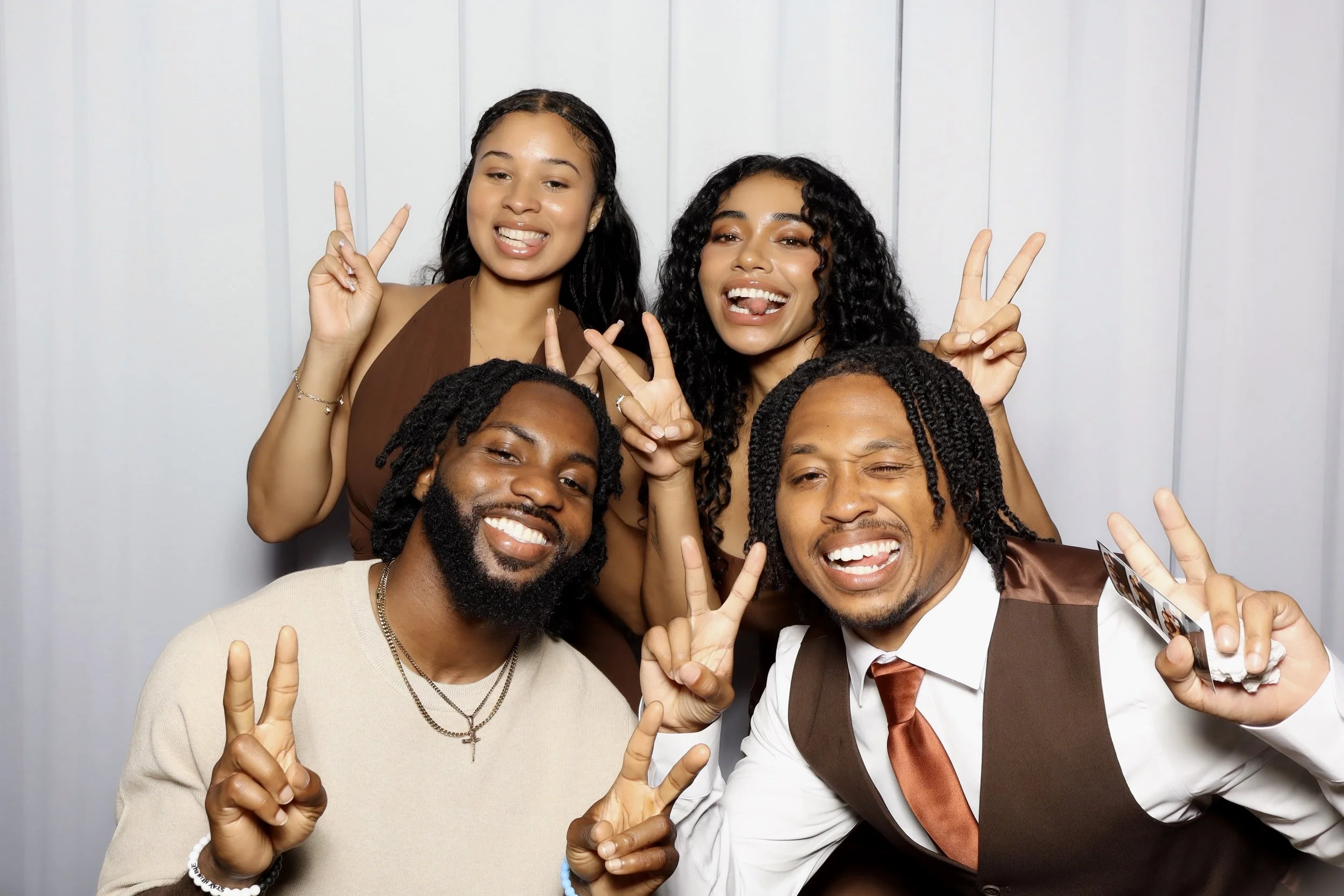 4 people putting the peace sign up posing for a Photo Booth