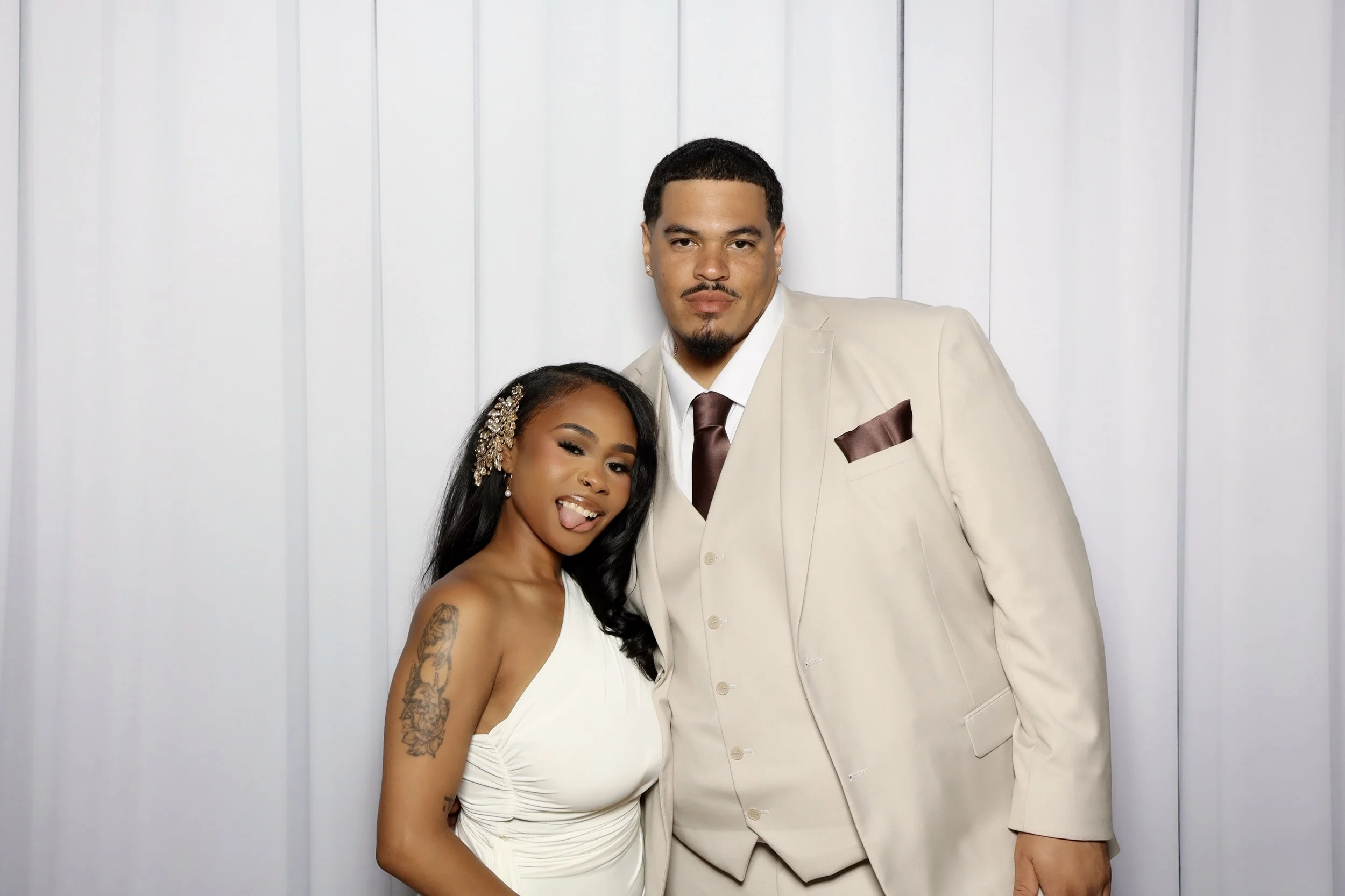 Bride and groom posing against a drape background.