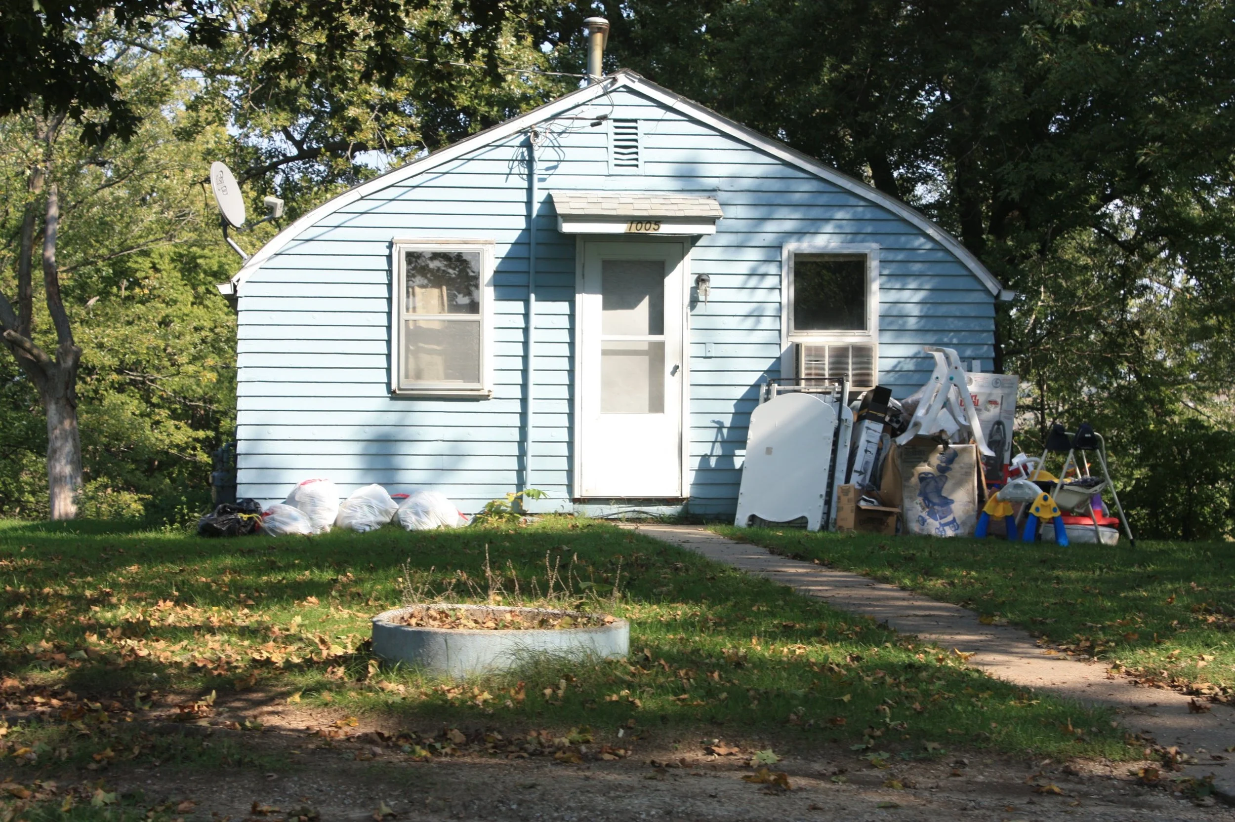 Small blue house with junk outside