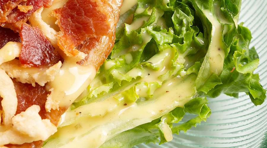 bacon, lettuce, salad with dressing on a green glass plate.
