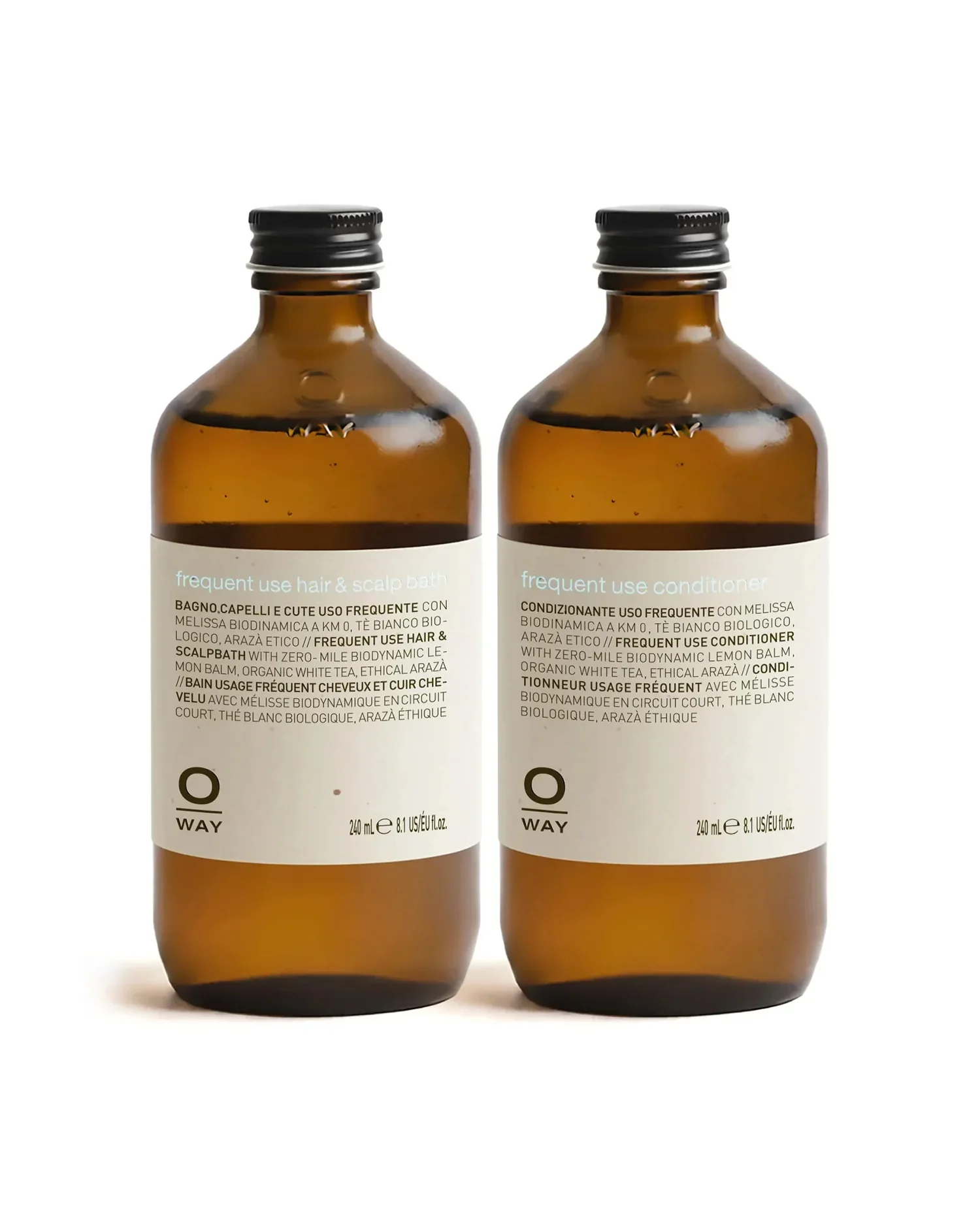 Two amber glass bottles with black caps and white labels containing hair and scalp care products, placed side by side on a white background.