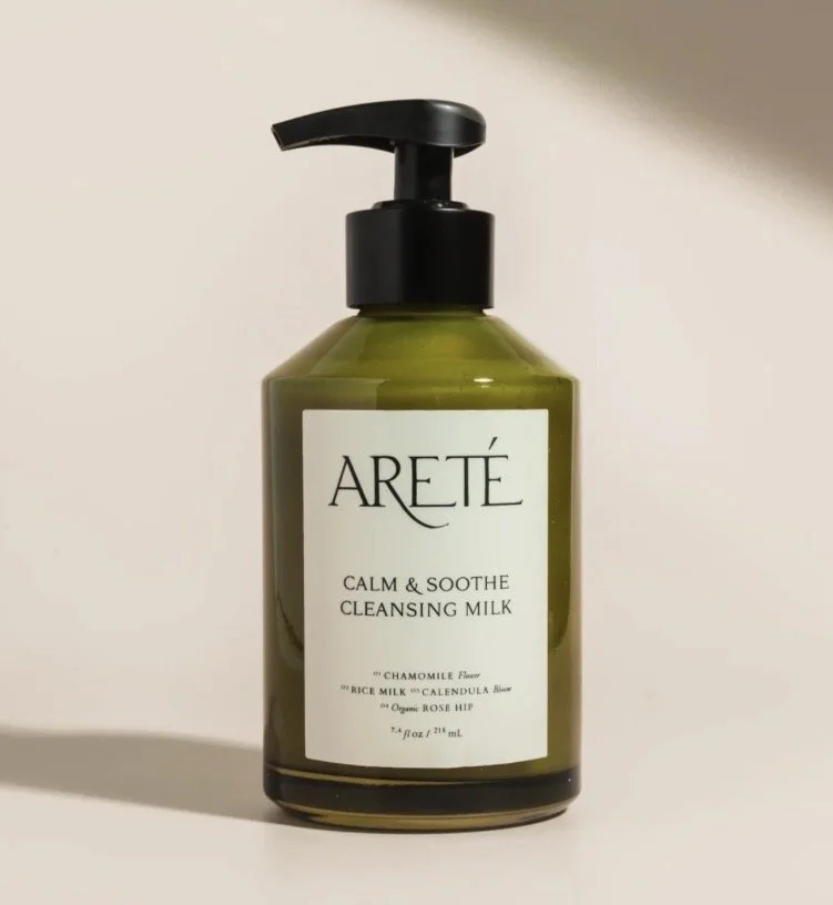 A green bottle of ARETÉ Calm & Soothe Cleansing Milk with a pump dispenser.