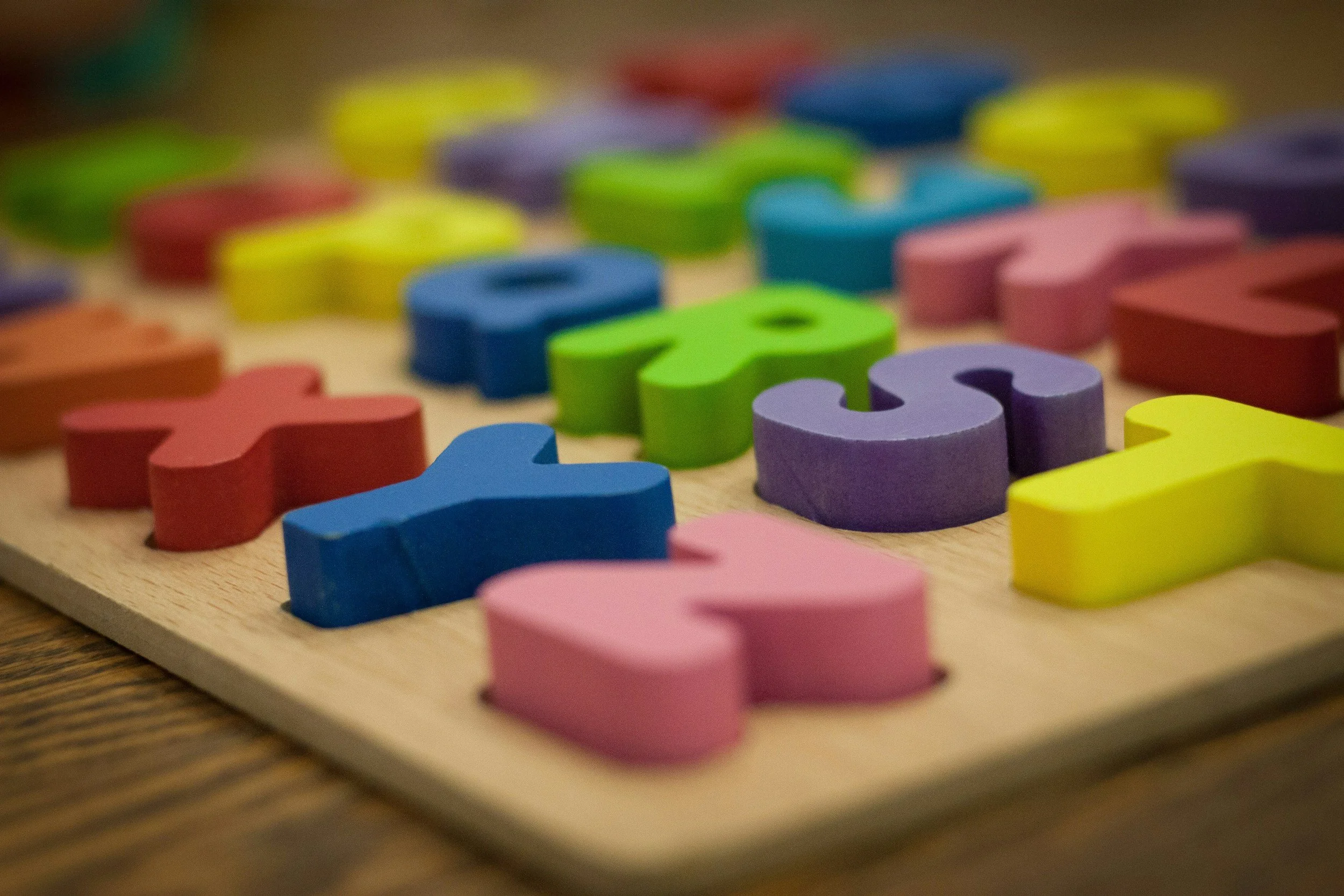 Colourful wooden puzzle pieces used in speech sound disorder therapy, early language and AAC for children