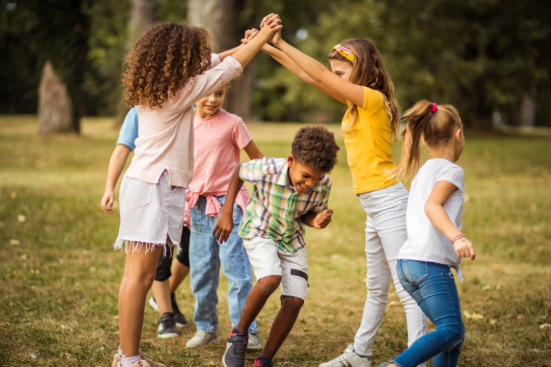 Group of children playing and celebrating together outdoors with good communication skills.