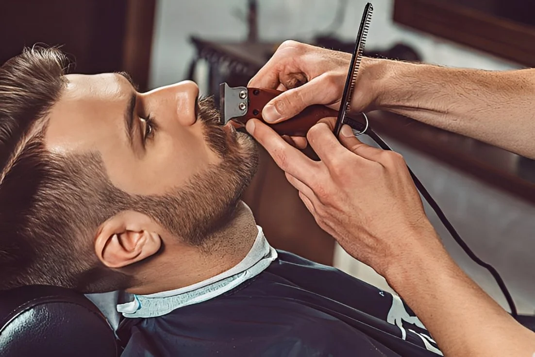 A man receiving a chin shave from a barber using a straight razor in a barbershop.